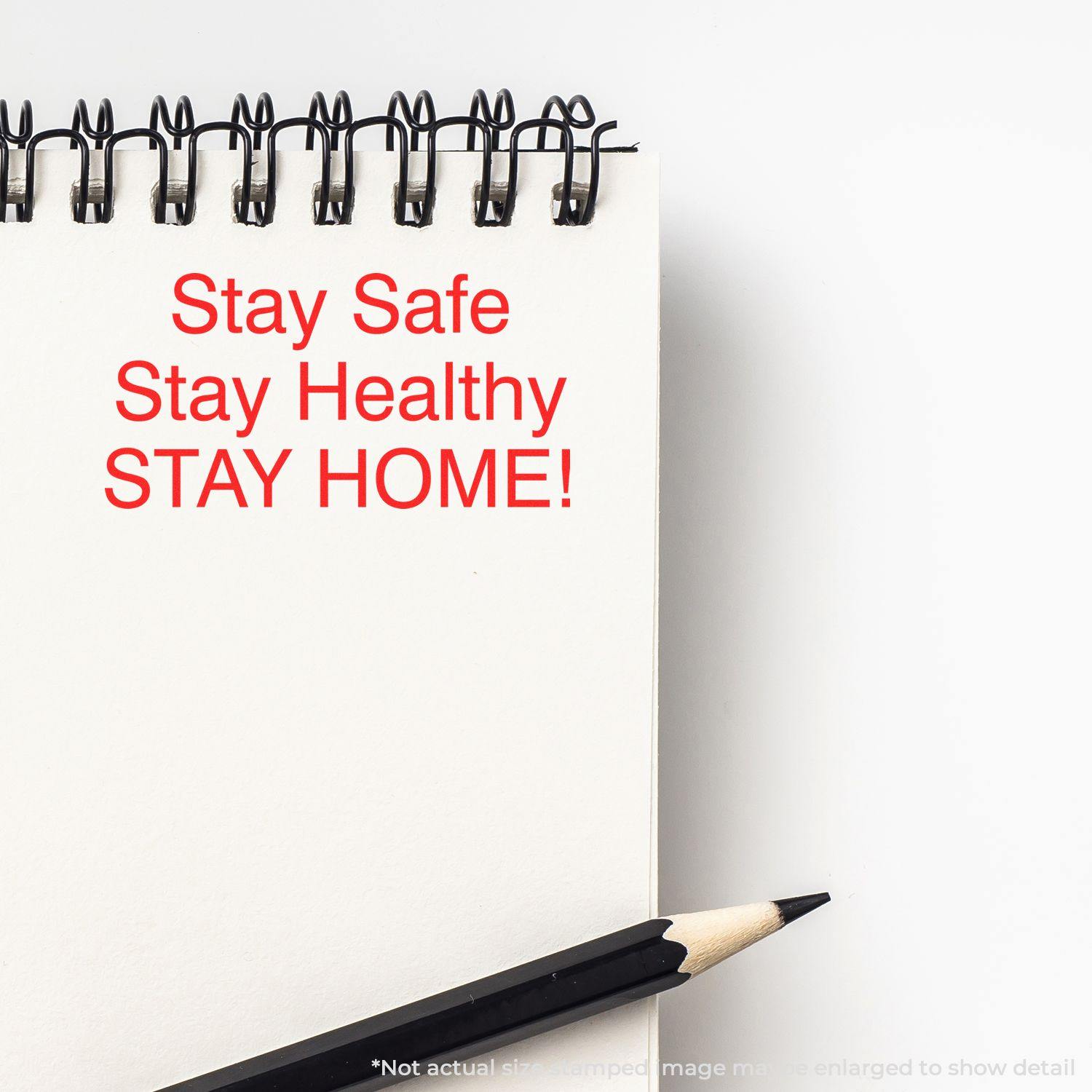 A notebook with Stay Safe Stay Healthy STAY HOME! stamped in red using the Large Pre-Inked Stay Safe Stay Healthy Stamp, next to a pencil.