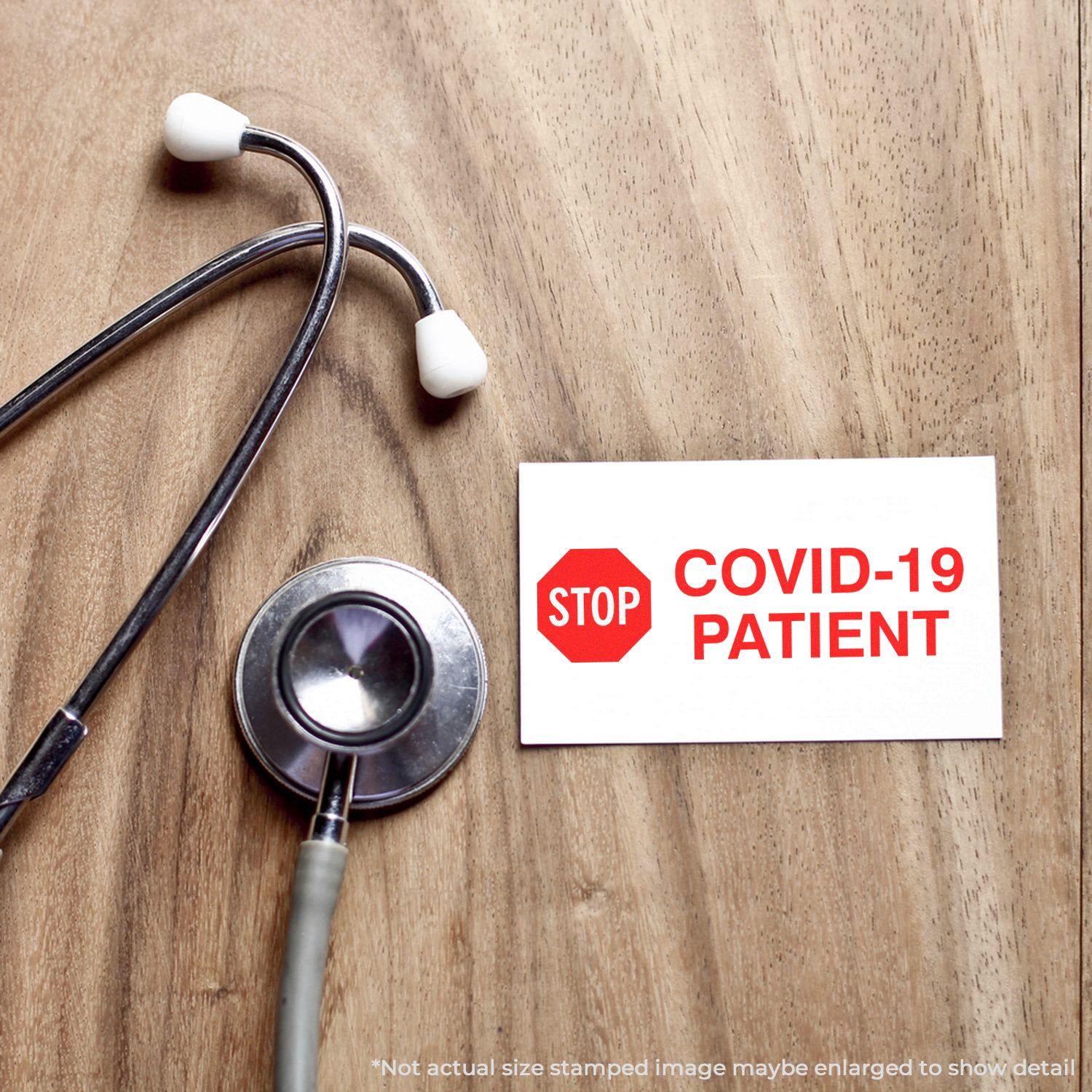 Stethoscope next to a card stamped with STOP COVID-19 PATIENT using the Large Pre-Inked Stop Covid-19 Patient Stamp on a wooden surface.