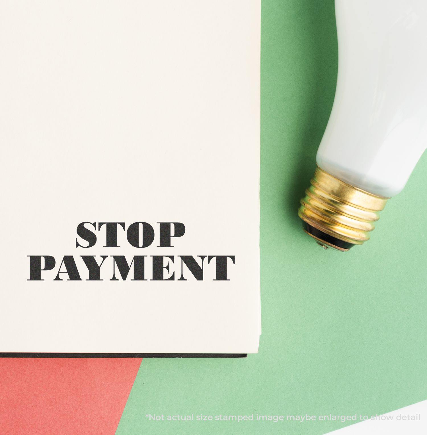 Large Pre-Inked Stop Payment Stamp used on a white paper, with a light bulb and colored paper in the background.