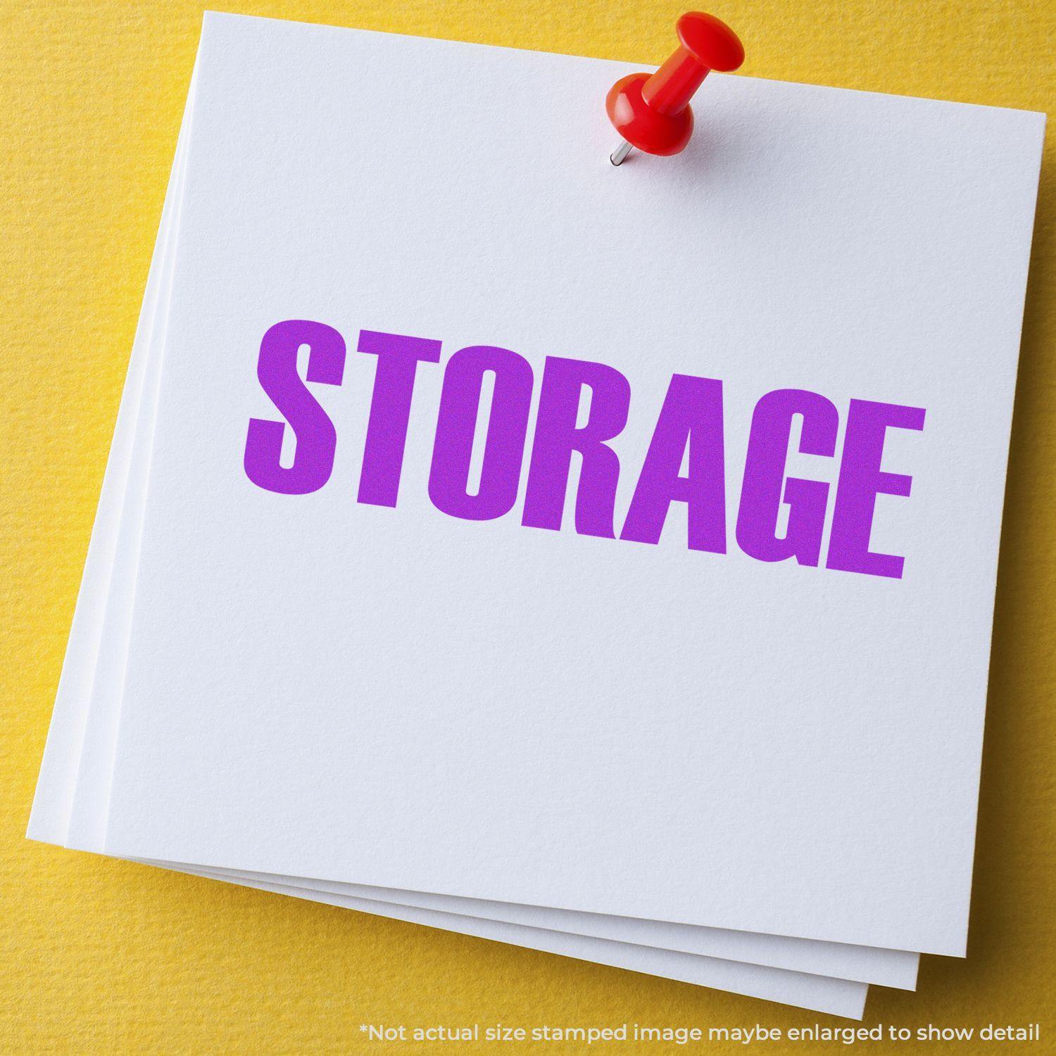 A stack of white papers stamped with STORAGE in purple ink using the Large Pre-Inked Storage Stamp, pinned with a red pushpin on a yellow surface.