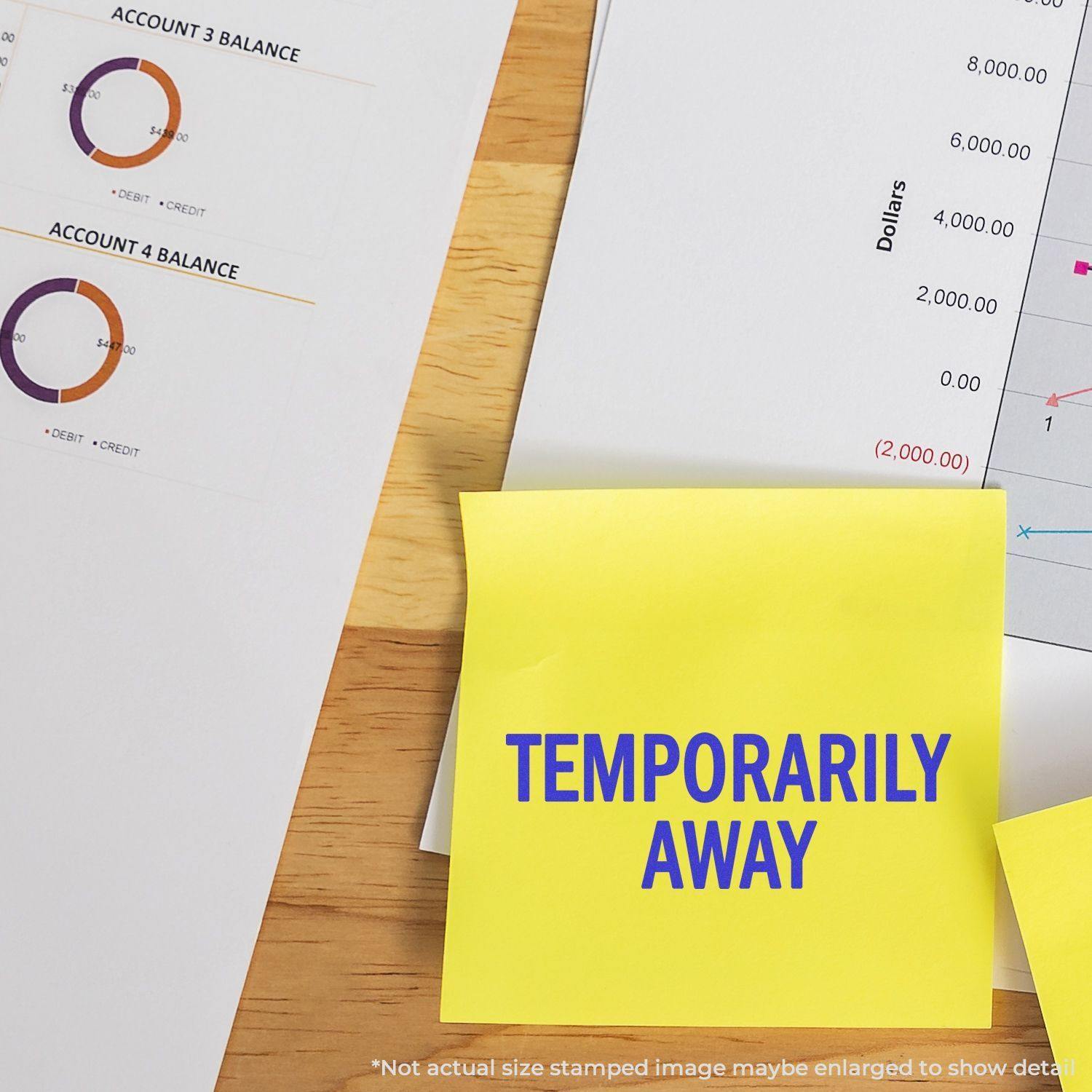 Temporarily Away Self Inking Stamp marking a yellow sticky note on a desk with financial documents & charts in the background