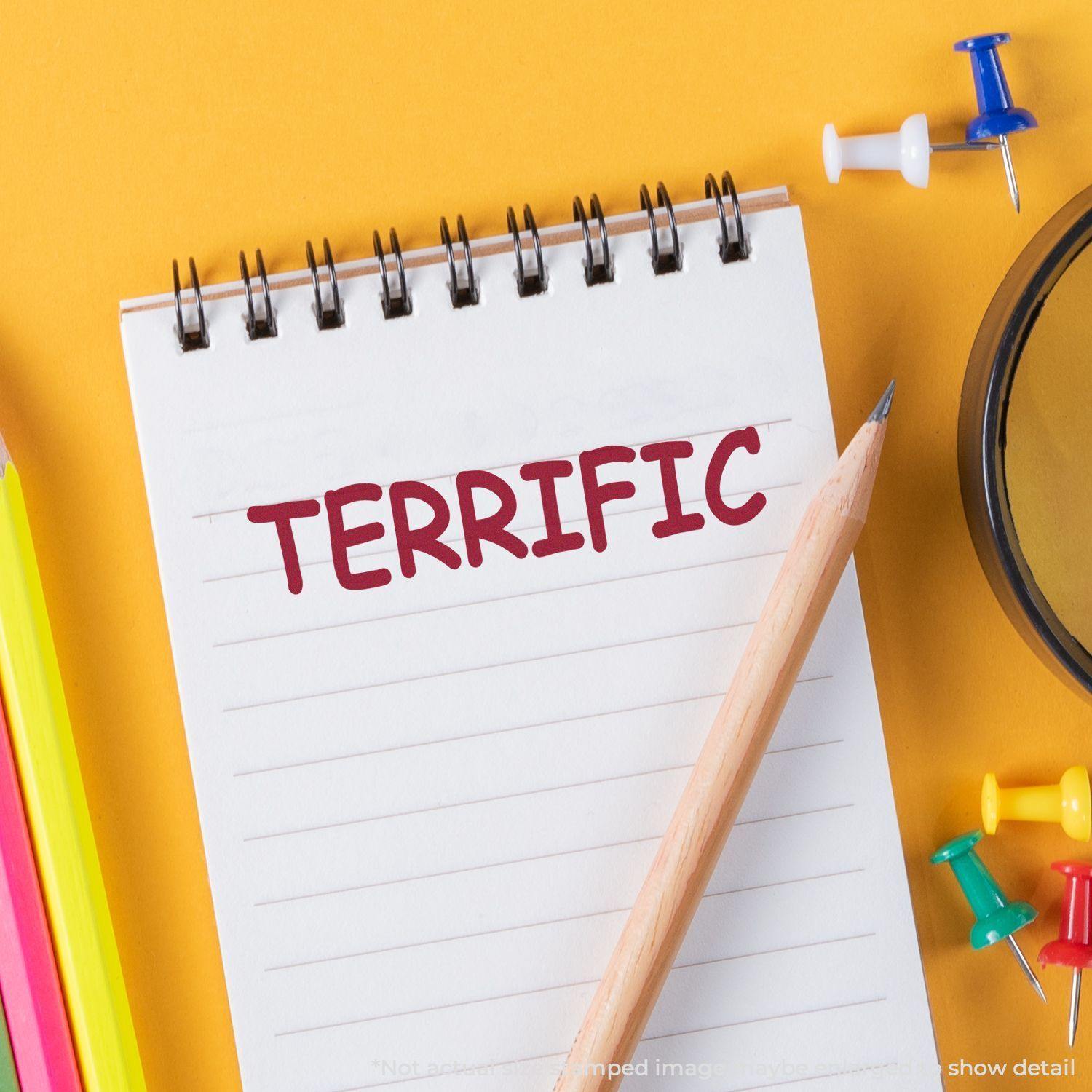 A Self Inking Terrific Stamp is used on a notepad with the word TERRIFIC stamped in red ink, surrounded by stationery items.