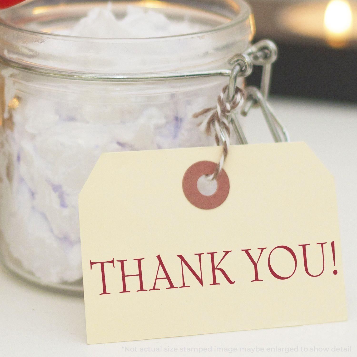 A thank you rubber stamp on a tag attached to a glass jar filled with white crumpled paper, creating a warm and appreciative message.