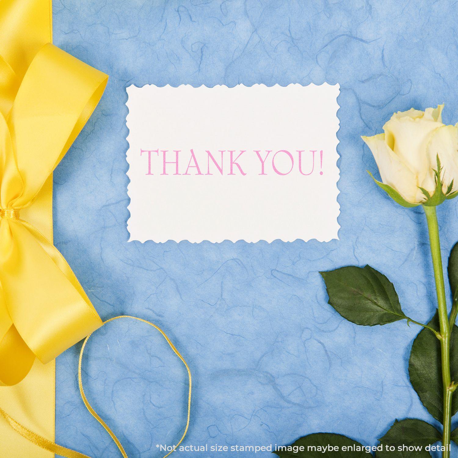 A Large Pre-Inked Thank You Stamp on a white card with a yellow ribbon and rose on a blue textured background.