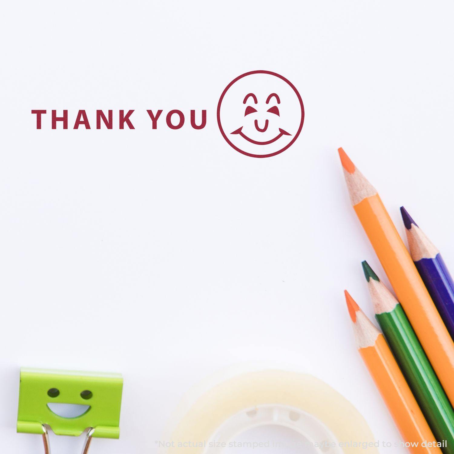 Slim Pre-Inked Thank You with Smiley Stamp on white paper, surrounded by colorful pencils, a smiley clip, and tape.