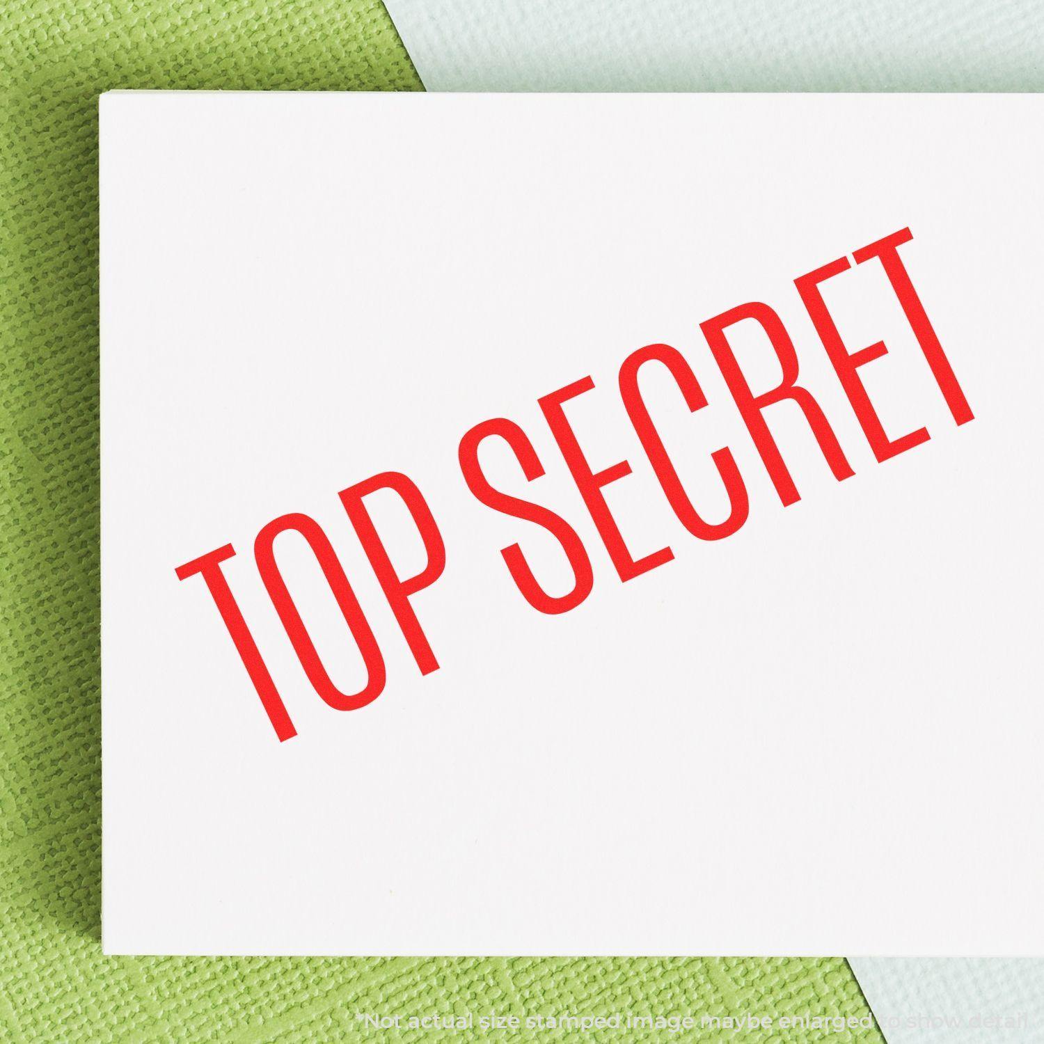 Large Pre-Inked Top Secret Stamp in red ink on white paper, angled text, placed on a green and white textured background.