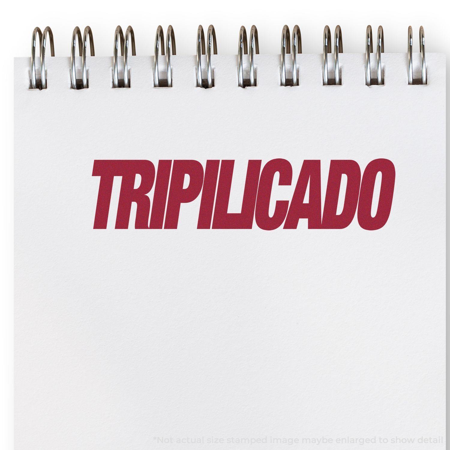 A self-inking stamp with a stamped image showing how the text "TRIPILICADO" in a large italic font is displayed by it after stamping.
