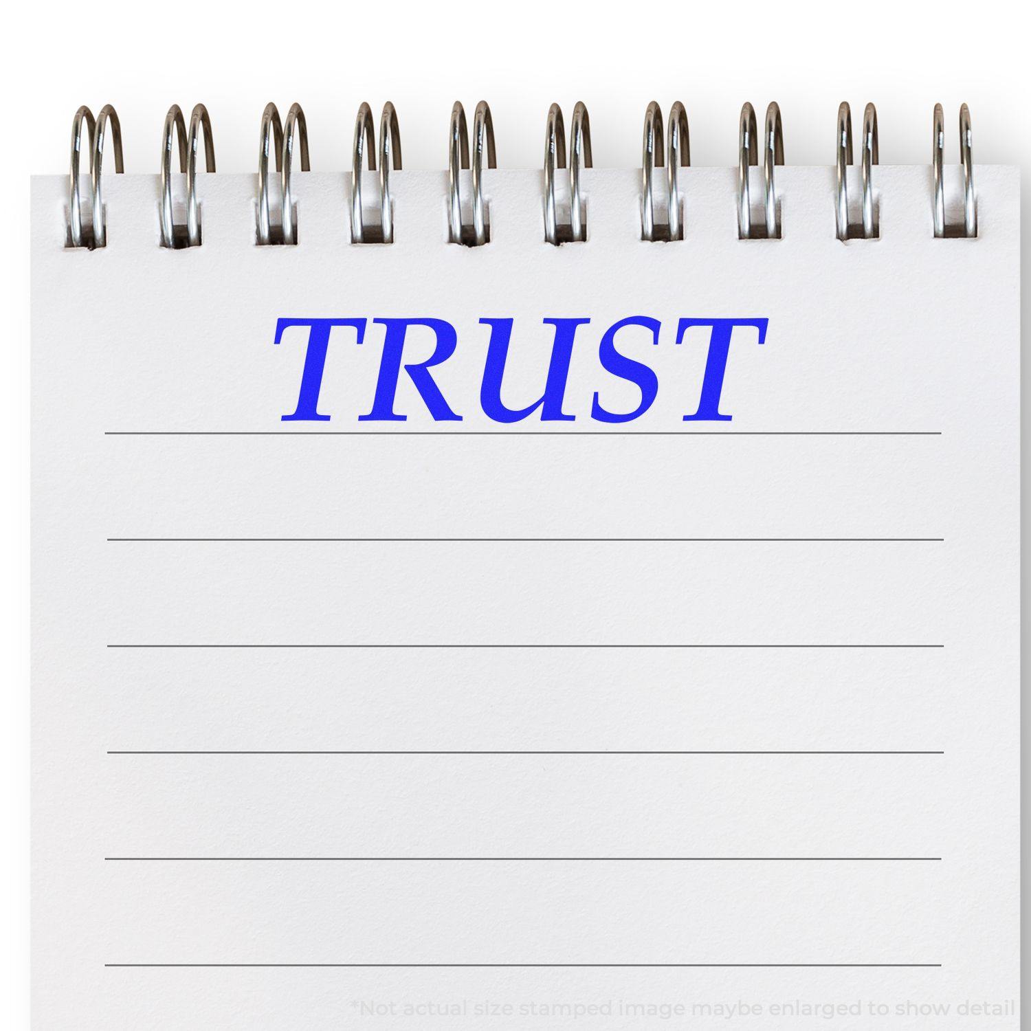 A notepad with TRUST stamped in blue ink using a Self Inking Trust Stamp. The stamp is clear and bold on the lined paper.