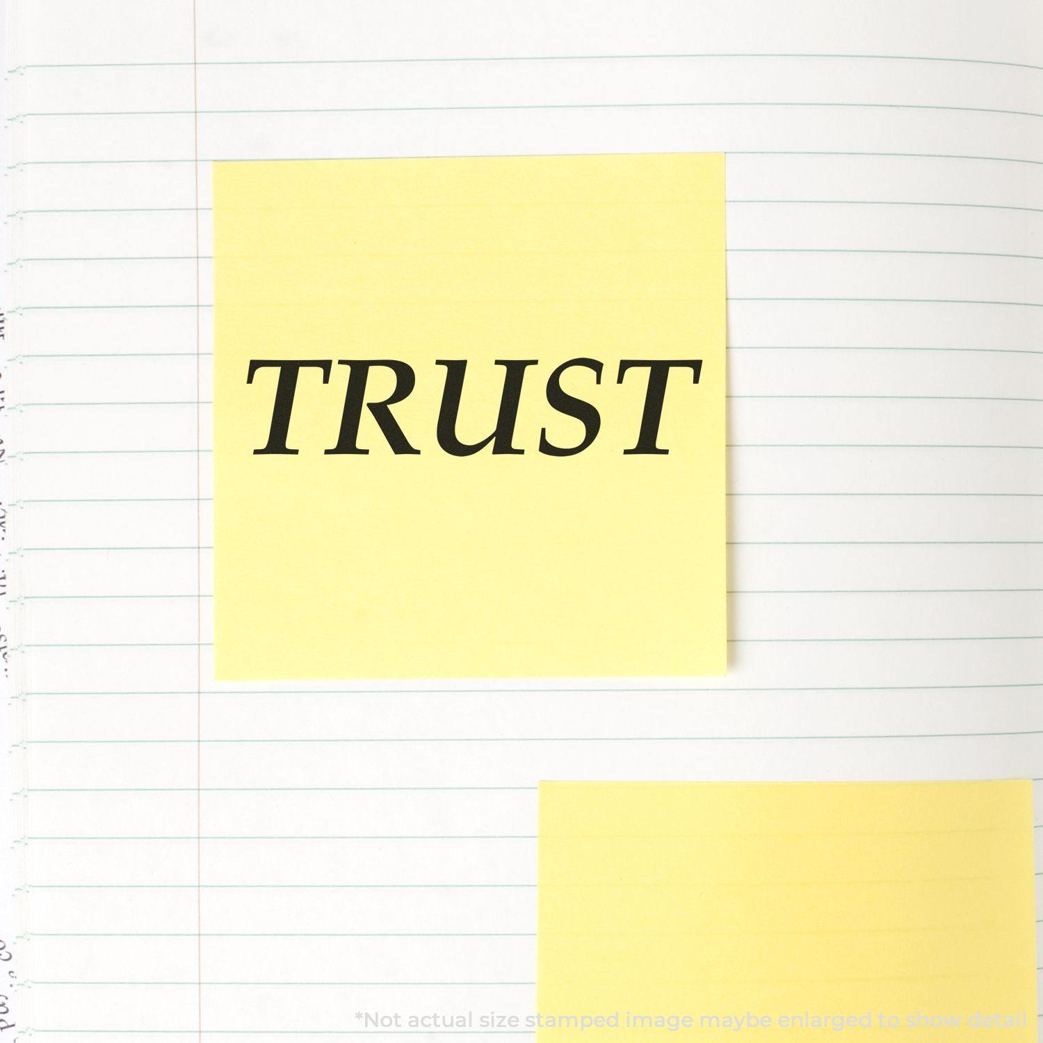 Large Trust Rubber Stamp impression on a yellow sticky note placed on a lined notebook page.