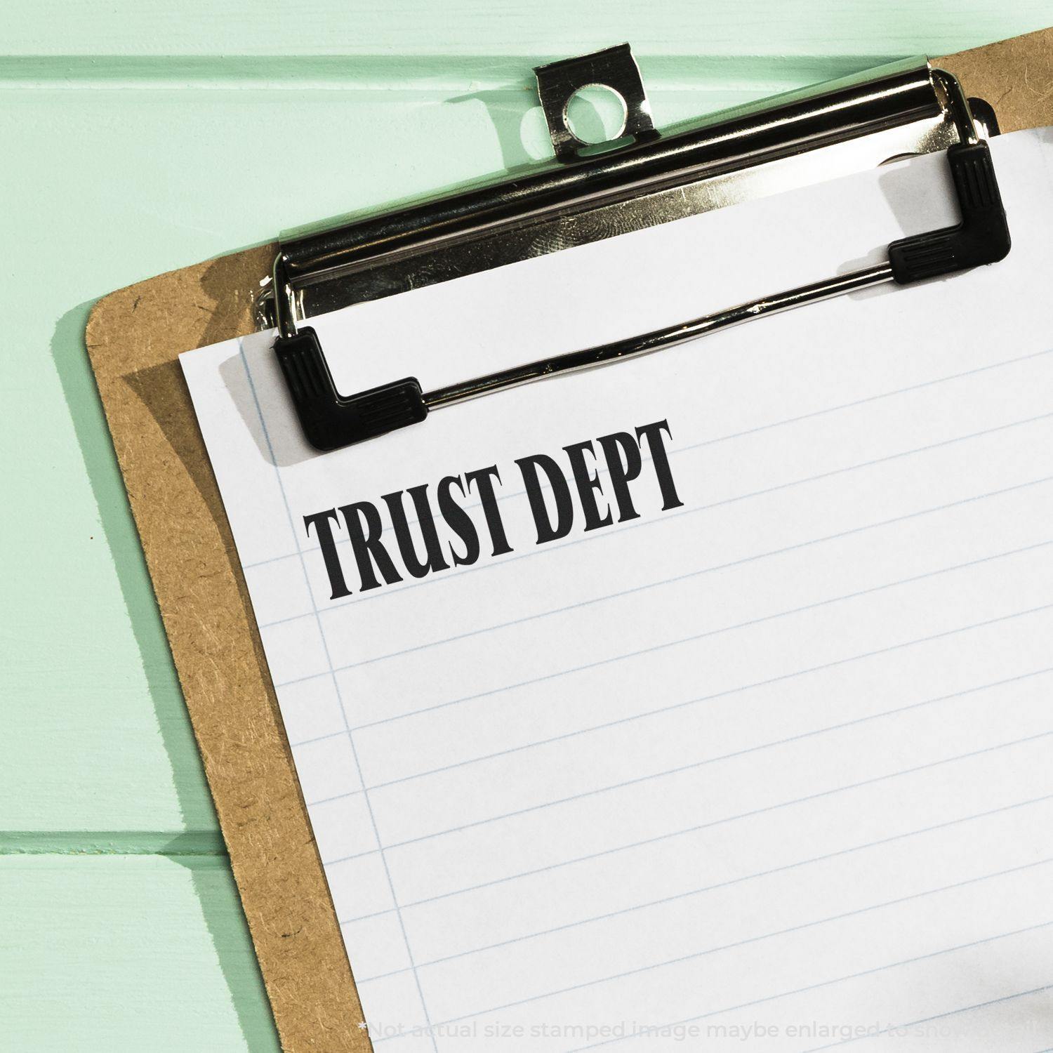 Clipboard with lined paper stamped Trust Dept in bold black letters, representing a Trust Dept rubber stamp in use.