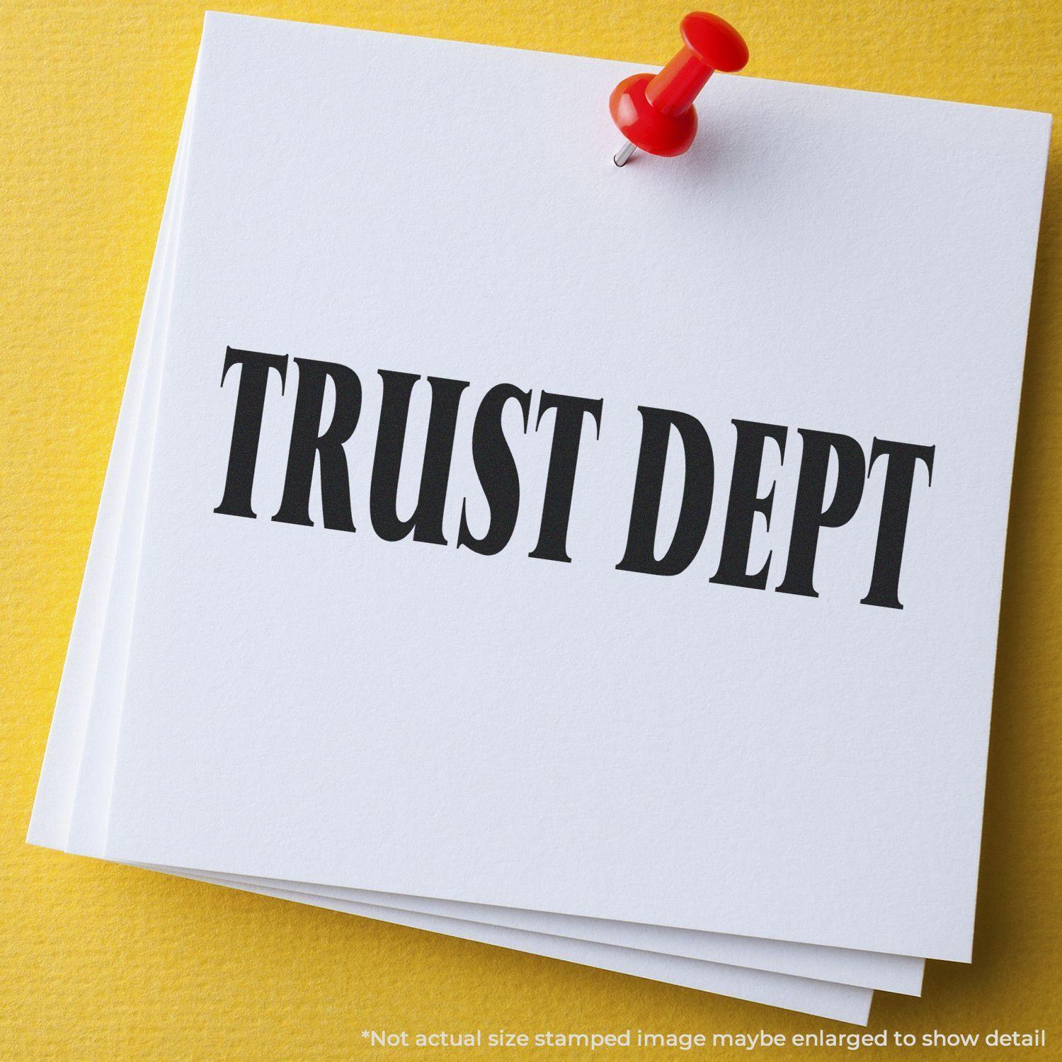 A large rubber stamp with the text TRUST DEPT on white paper, pinned with a red pushpin on a yellow background.