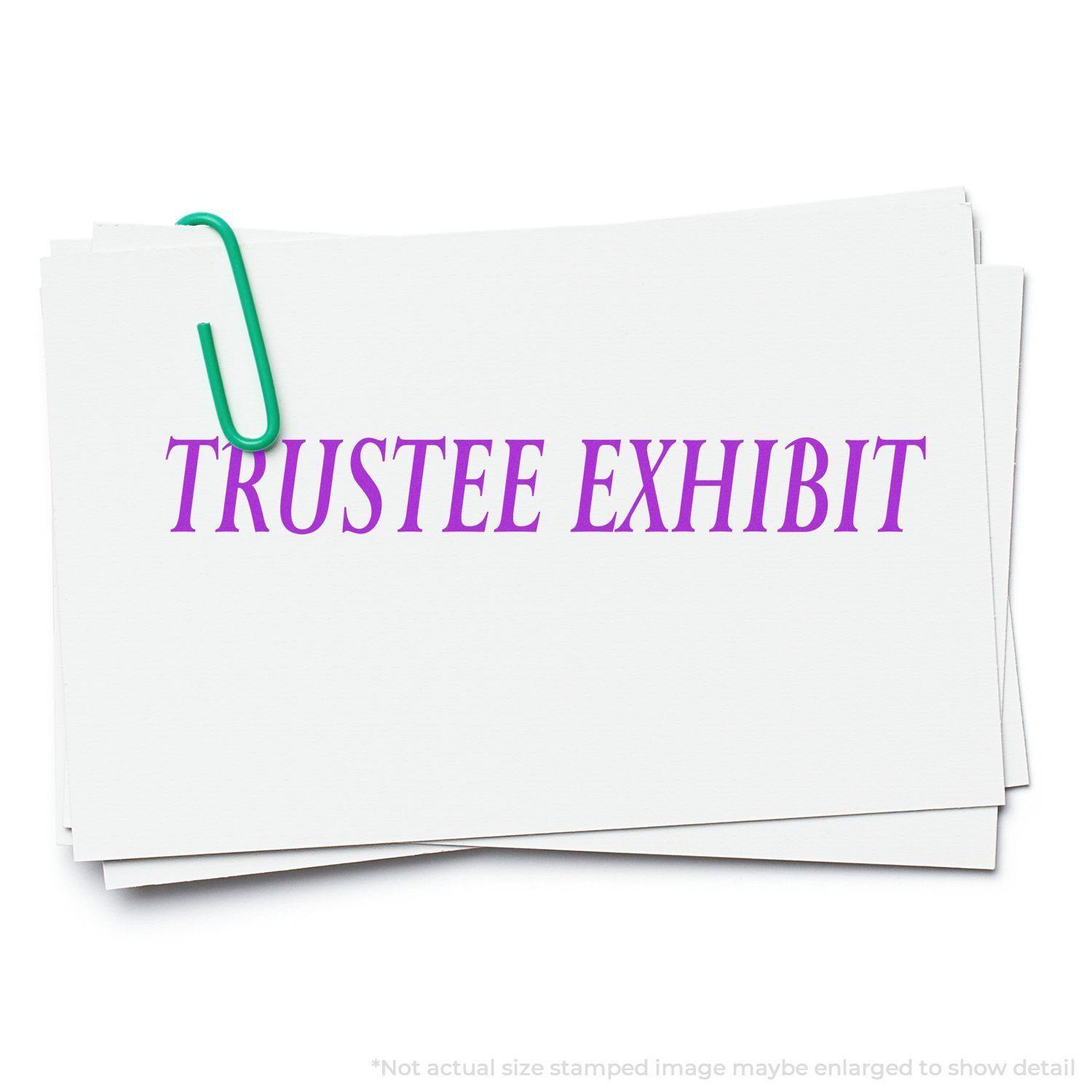 A stack of white papers with TRUSTEE EXHIBIT stamped in purple using the Self Inking Trustee Exhibit Stamp, held together by a green paperclip.