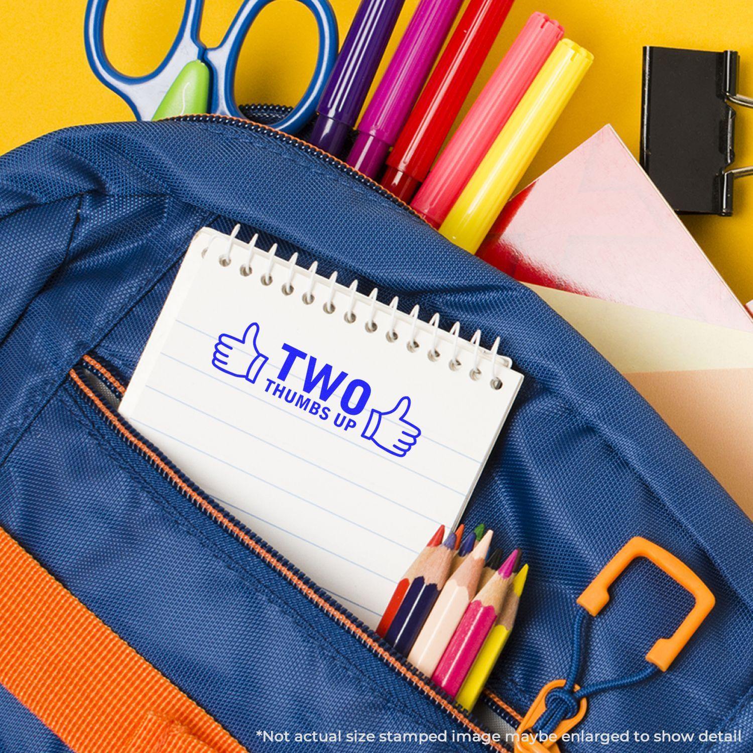 A blue backpack with school supplies and a notebook stamped with TWO THUMBS UP using the Self Inking Two Thumbs Up with Thumb Icon Stamp.