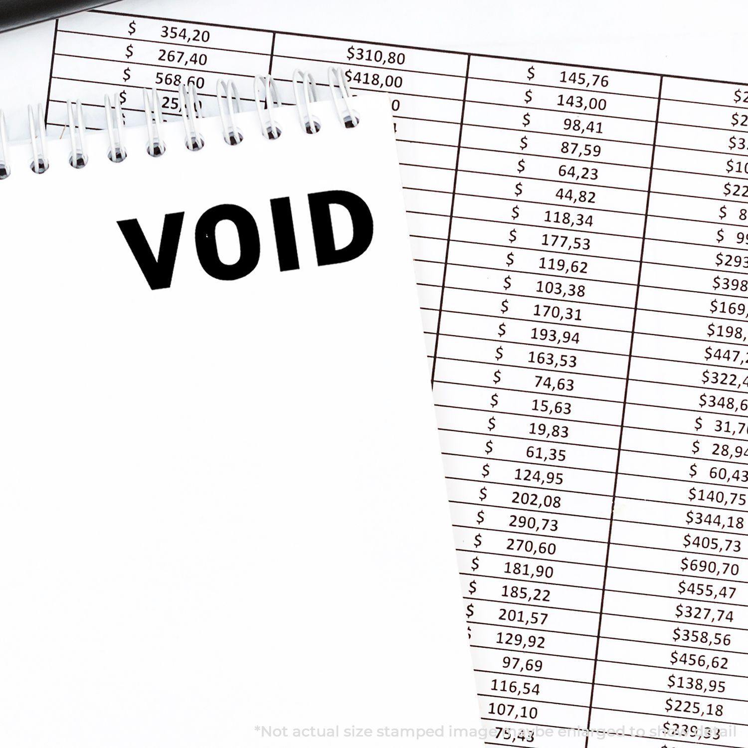 Slim Pre-Inked Void Stamp used on a notebook page with VOID text, placed next to a financial spreadsheet.