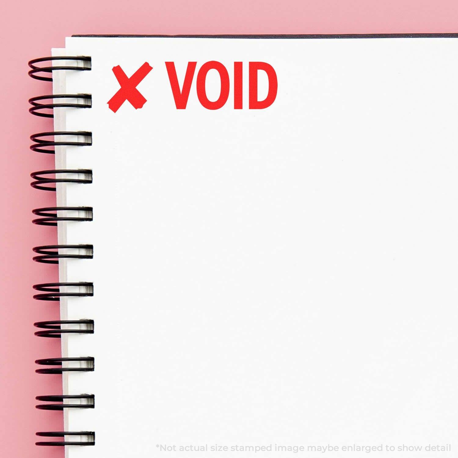 Large Pre-Inked Void with X Stamp used on a white spiral notebook, showing a red X and VOID text on a pink background.