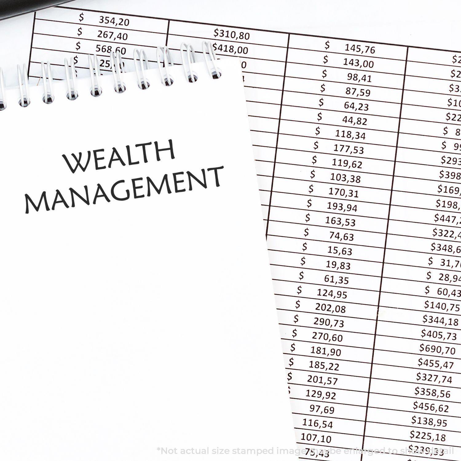 A Large Pre-Inked Wealth Management Stamp is used on a notepad with financial data sheets in the background.