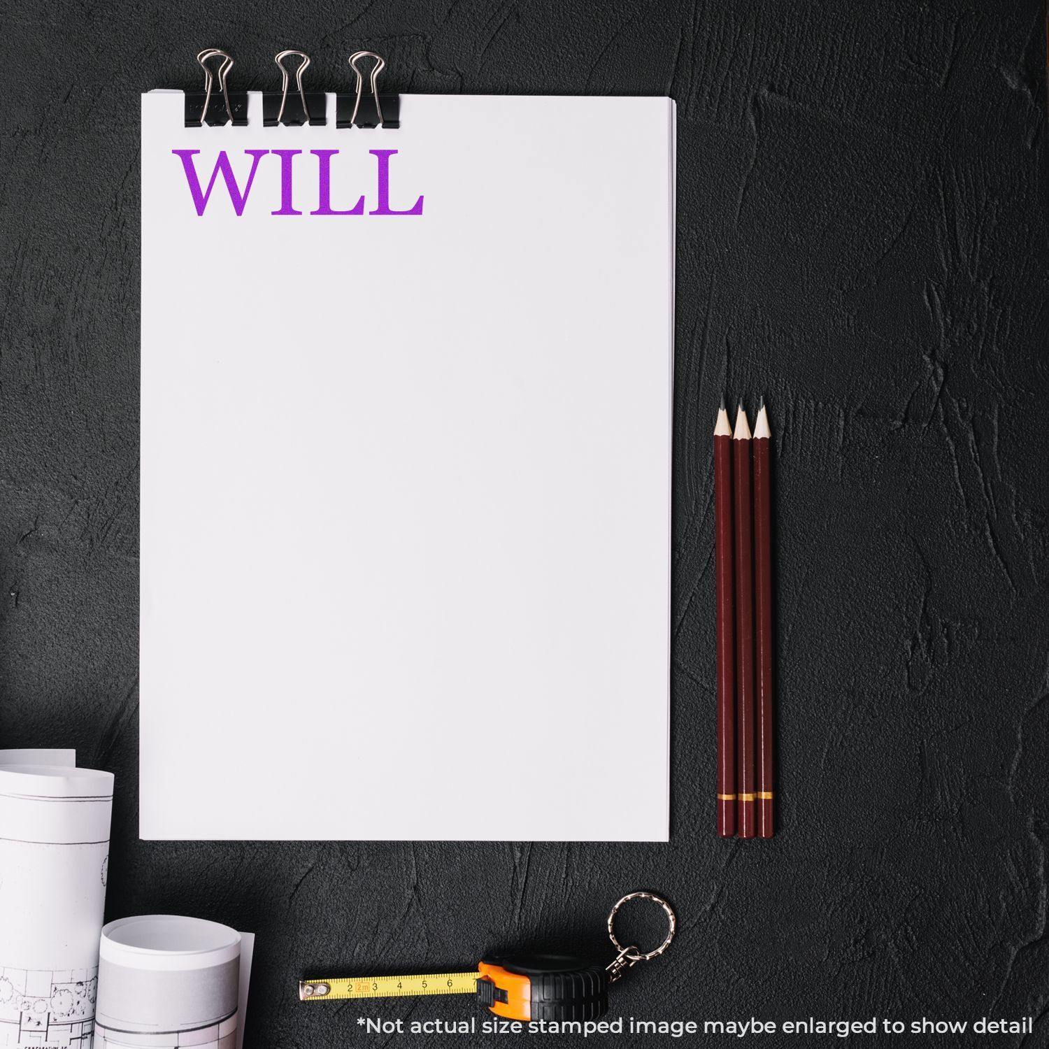 Large Pre-Inked Will Stamp used on a white sheet of paper with WILL in purple text, surrounded by pencils, a tape measure, and blueprints.