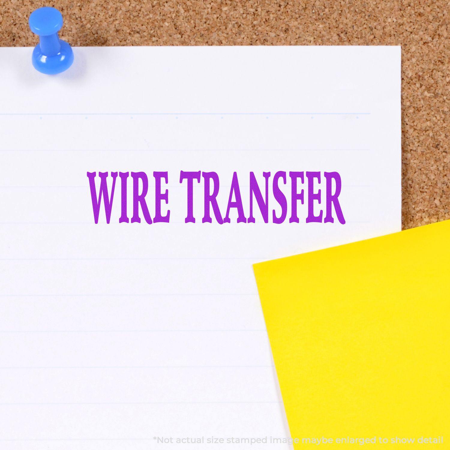 Self Inking Wire Transfer Stamp imprinting WIRE TRANSFER in purple ink on a white paper pinned to a corkboard with a yellow note.