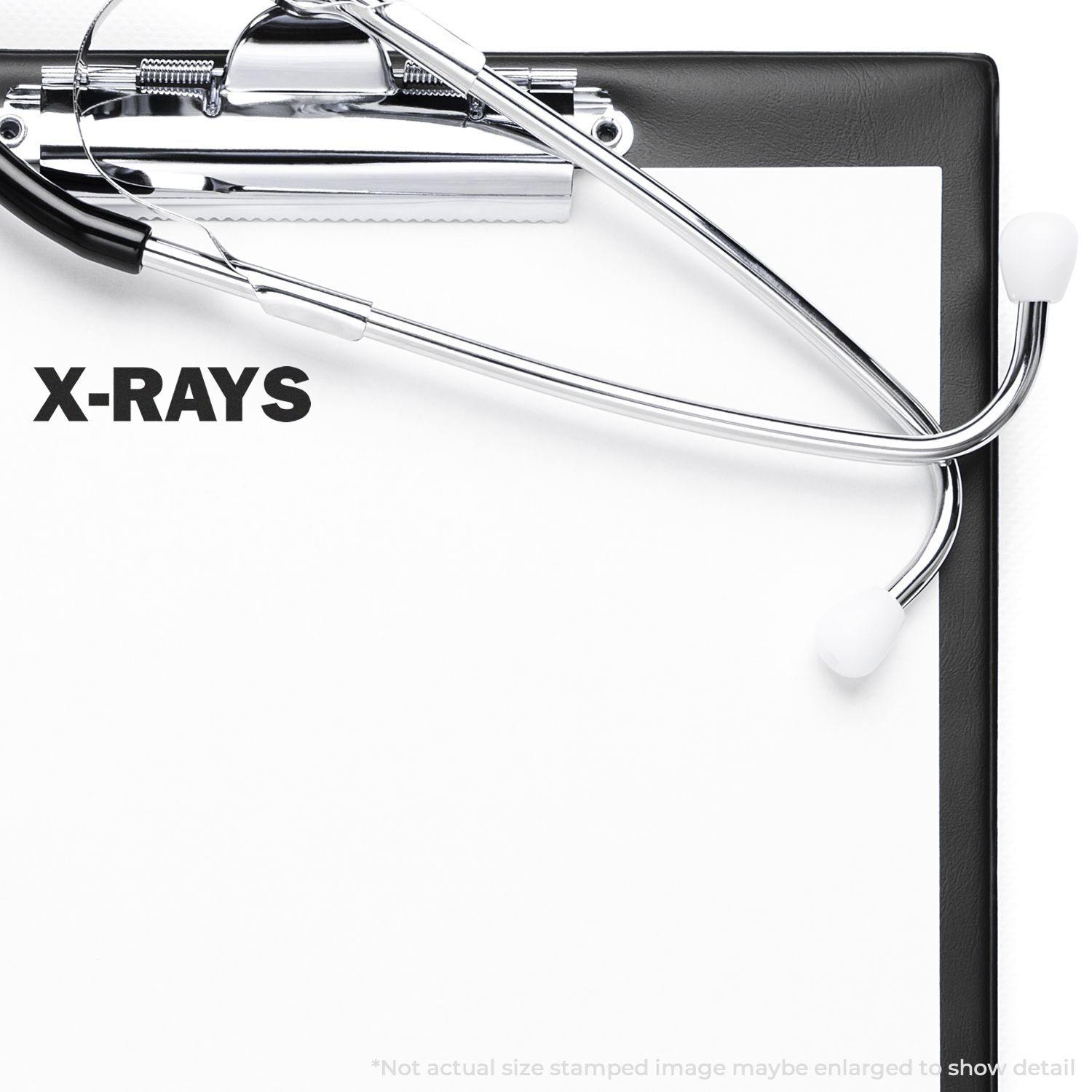 A self-inking stamp with a stamped image showing how the text "X-RAYS" in a large bold font is displayed by it after stamping.