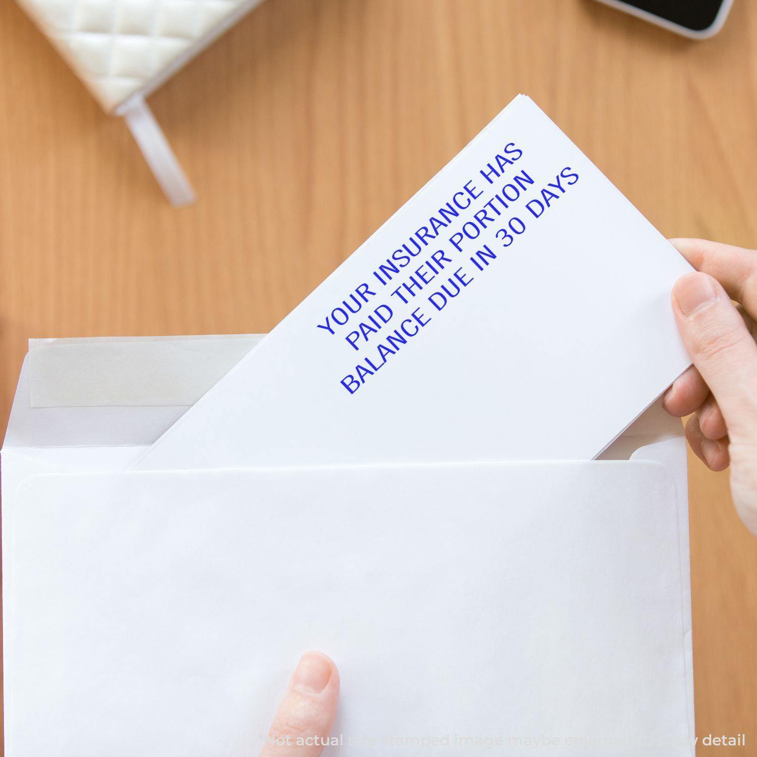 Person holding an envelope with a letter stamped YOUR INSURANCE HAS PAID THEIR PORTION BALANCE DUE IN 30 DAYS in blue text.