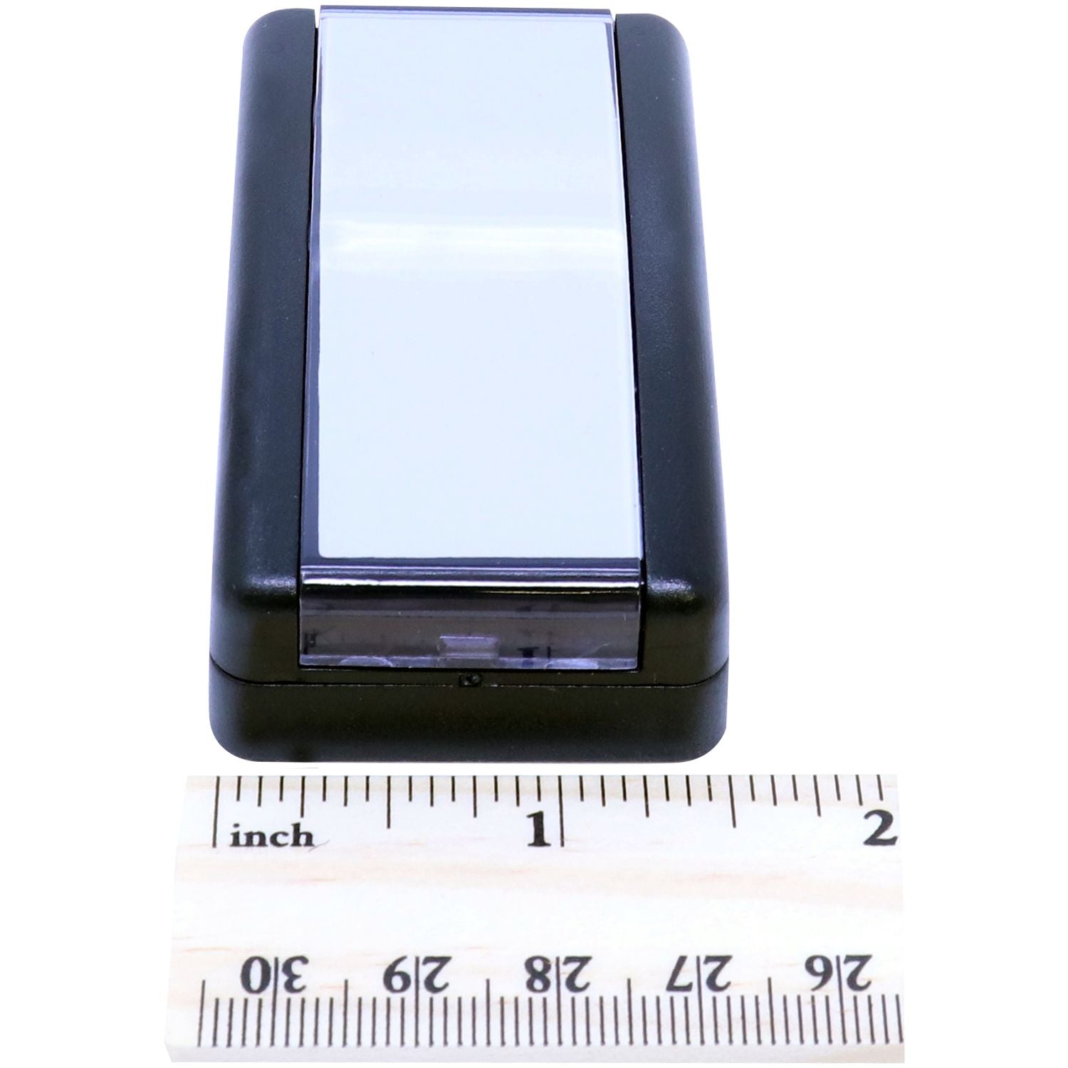 Super Slim 2564 Customized Pre-Inked Stamp 1 x 2-3/8 shown with a ruler for size reference. The stamp has a sleek black design with a white top.