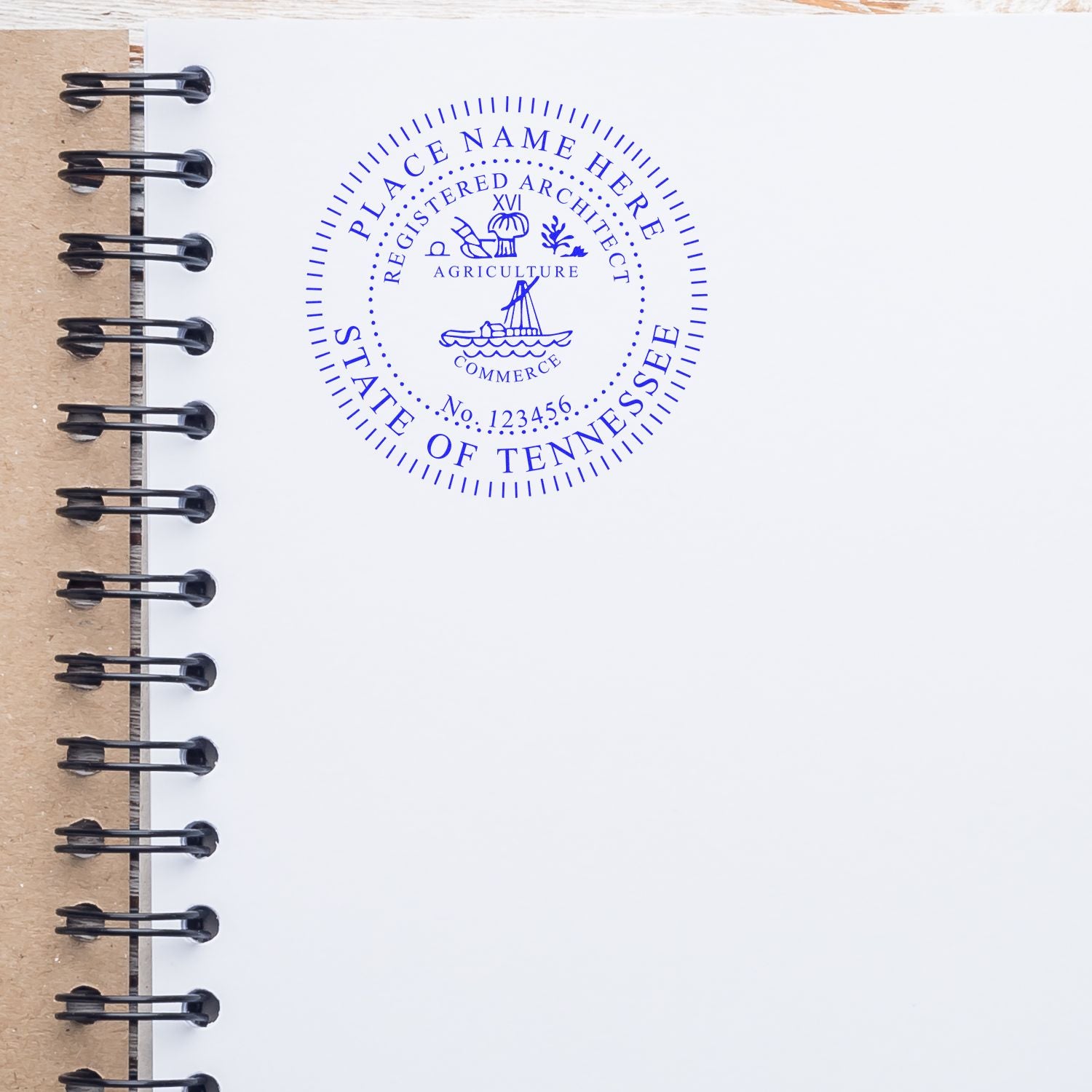 Premium MaxLight Pre-Inked Tennessee Architectural Stamp in blue ink on white paper, placed on an open spiral notebook.