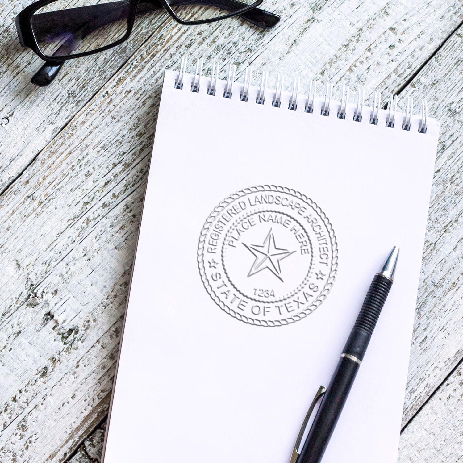 An in use photo of the Gift Texas Landscape Architect Seal showing a sample imprint on a cardstock