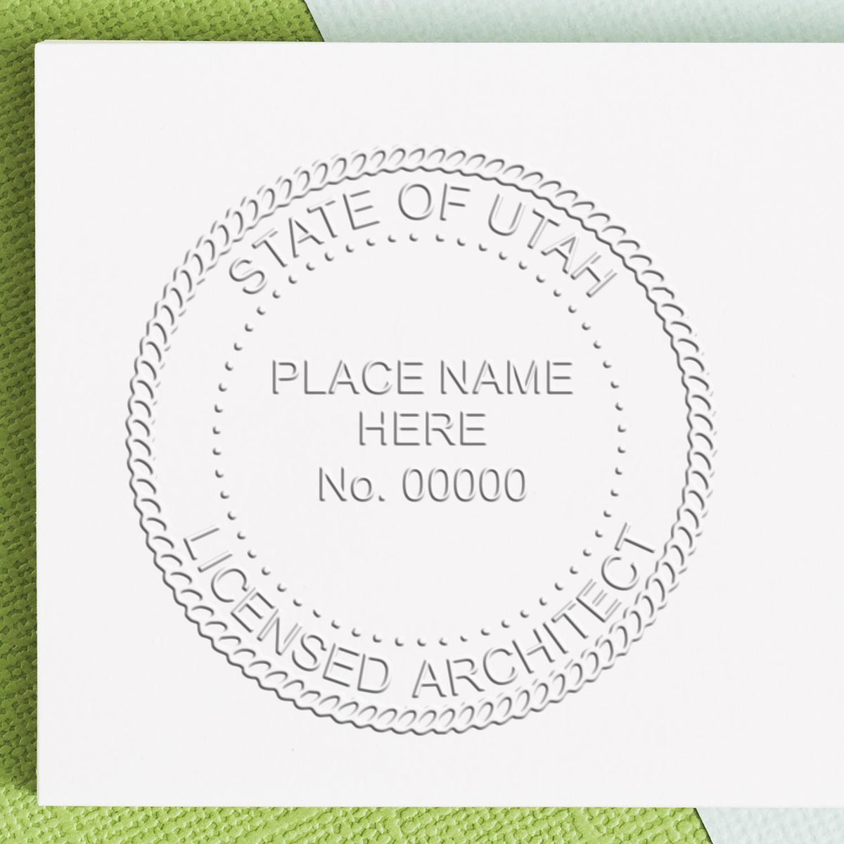 A lifestyle photo showing a stamped image of the Handheld Utah Architect Seal Embosser on a piece of paper