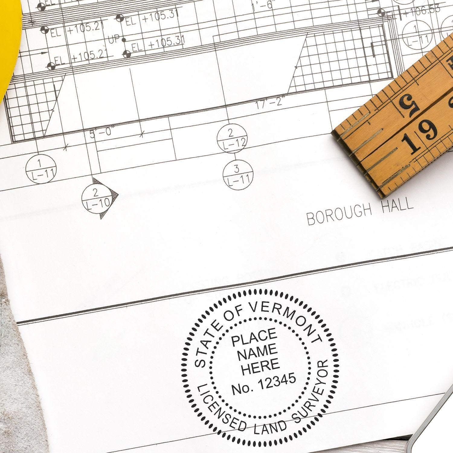 Blueprint with a Digital Vermont Land Surveyor Stamp, Electronic Seal for Vermont Land Surveyor, ruler, and yellow pencil on a desk.