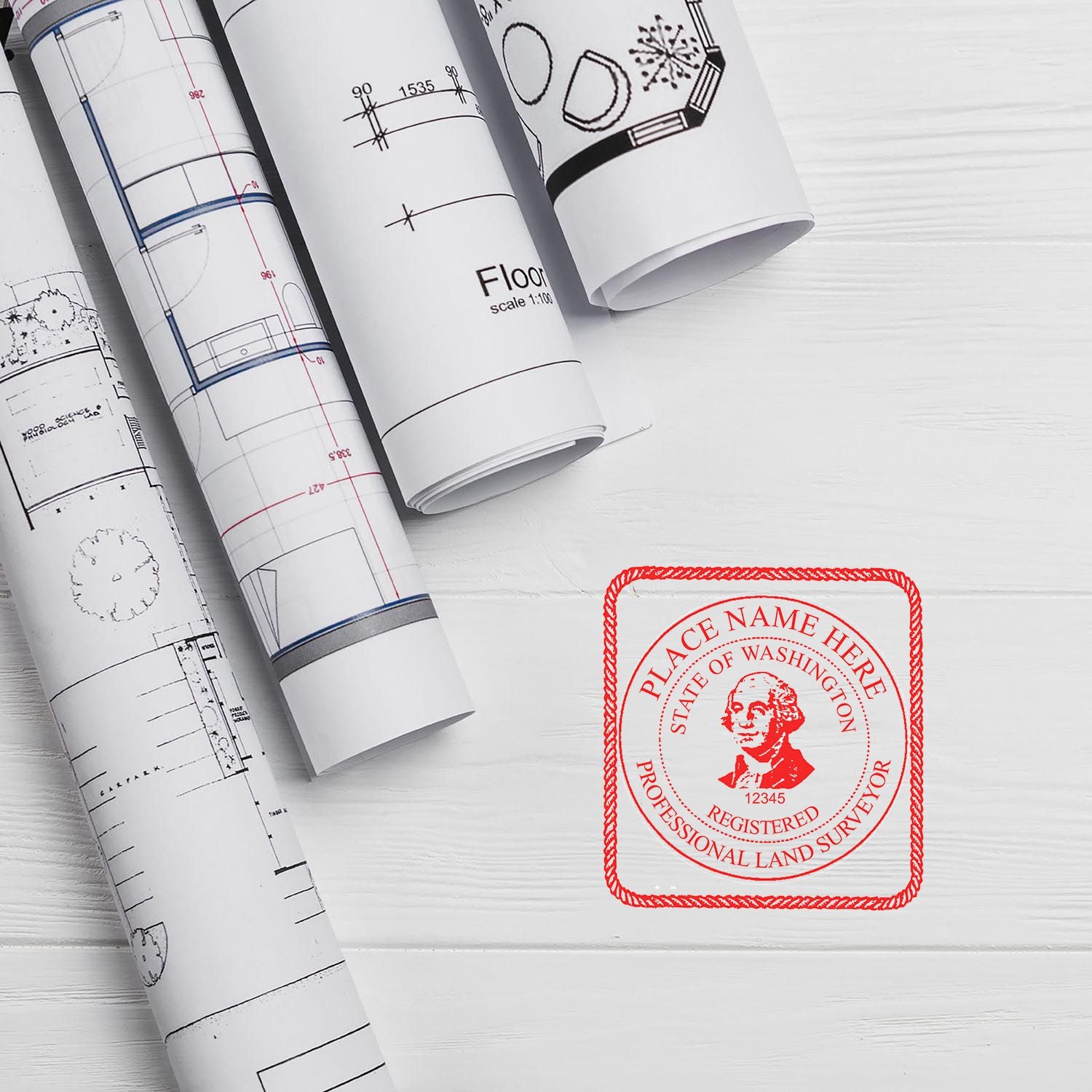 Land Surveyor MaxLight Pre Inked Rubber Stamp of Seal in red ink next to rolled architectural blueprints on a white wooden surface.