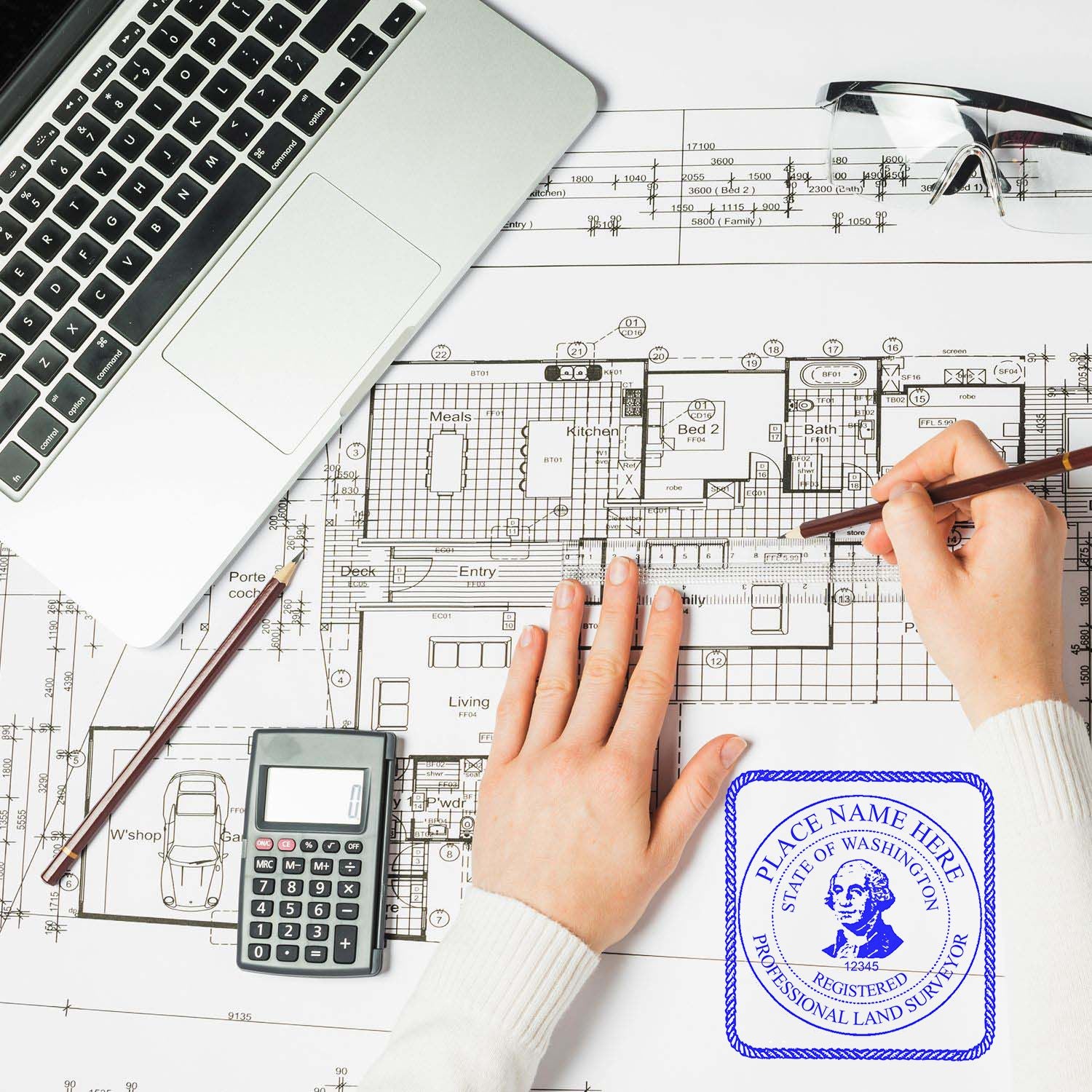 Person using the Digital Washington Land Surveyor Stamp, Electronic Seal for Washington Land Surveyor on architectural plans with a laptop and calculator.