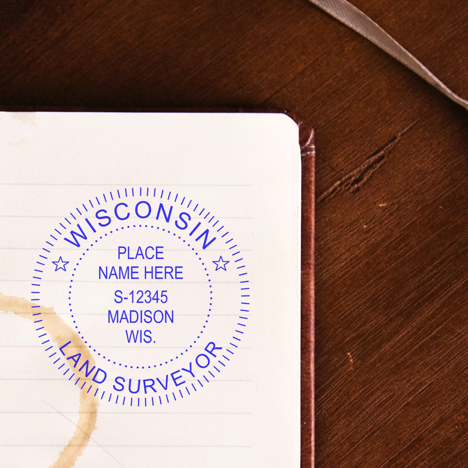 Premium MaxLight Pre-Inked Wisconsin Surveyors Stamp in blue ink on a notebook page with a coffee stain.