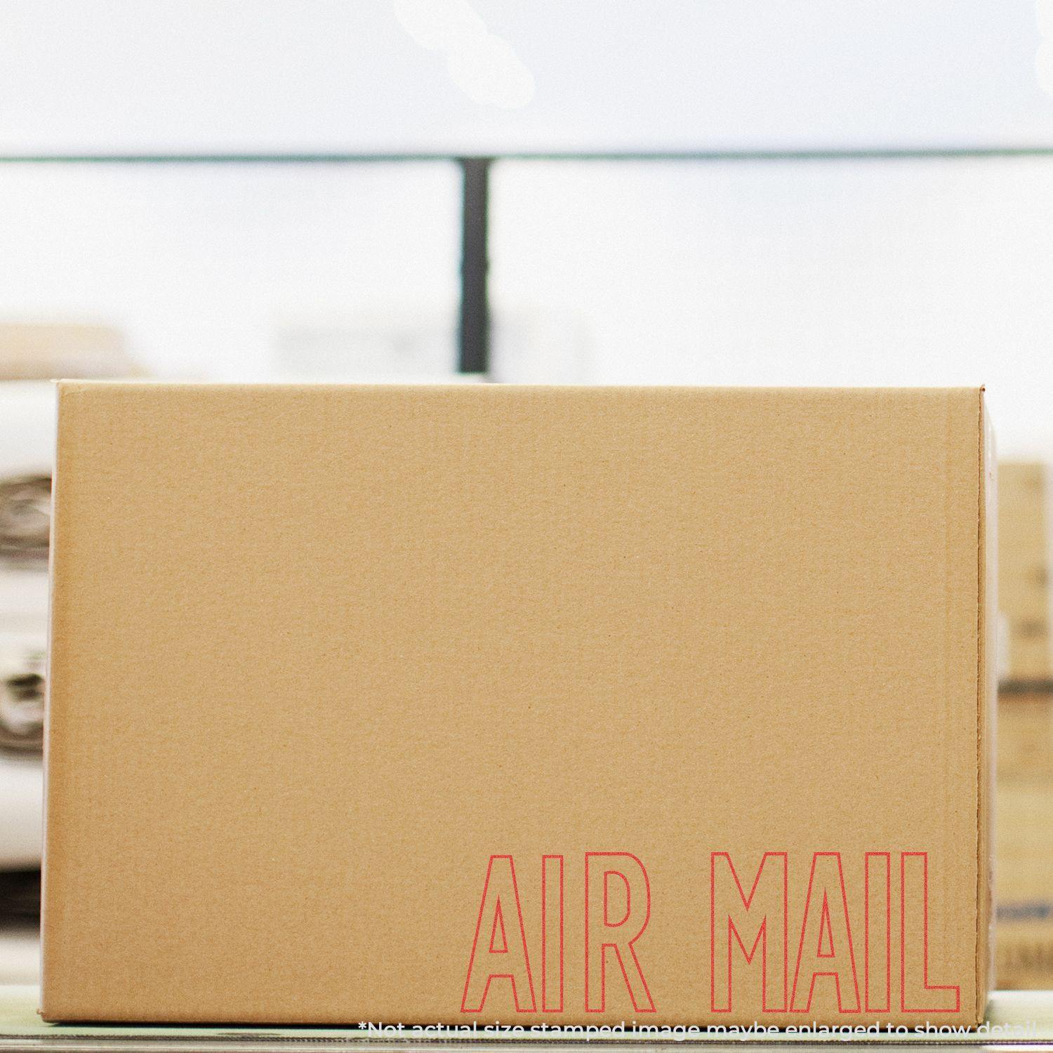 Cardboard box stamped with AIR MAIL in red using the Air Mail Xstamper Stamp, placed on a table with a blurred background.