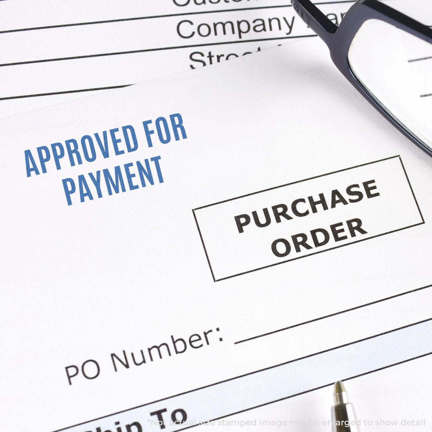 Close-up of a document with Approved For Payment Xstamper Stamp in blue, next to a purchase order form, pen, and glasses.