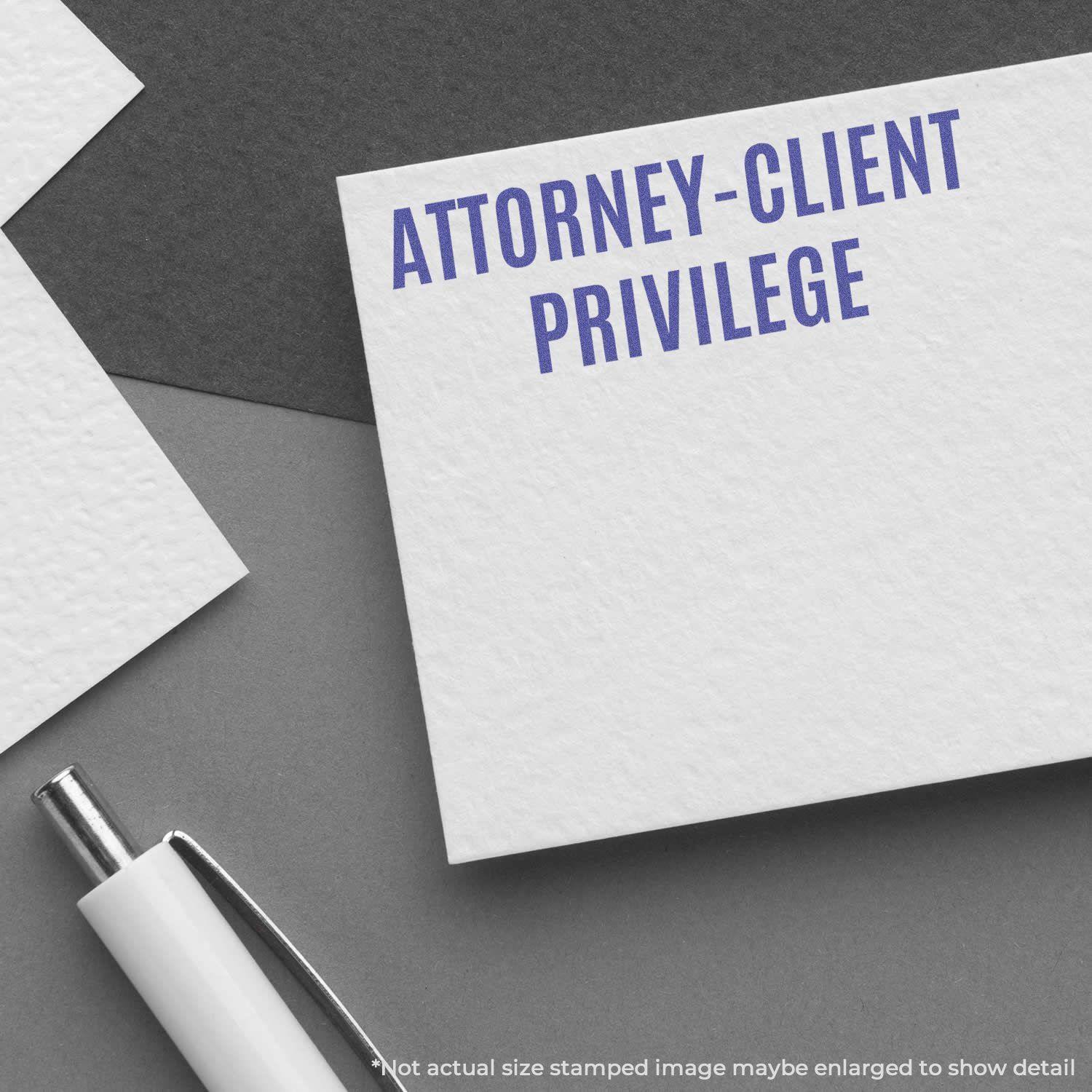 Attorney-Client Privilege Xstamper Stamp in use on a white card, with a pen and additional cards in the background.