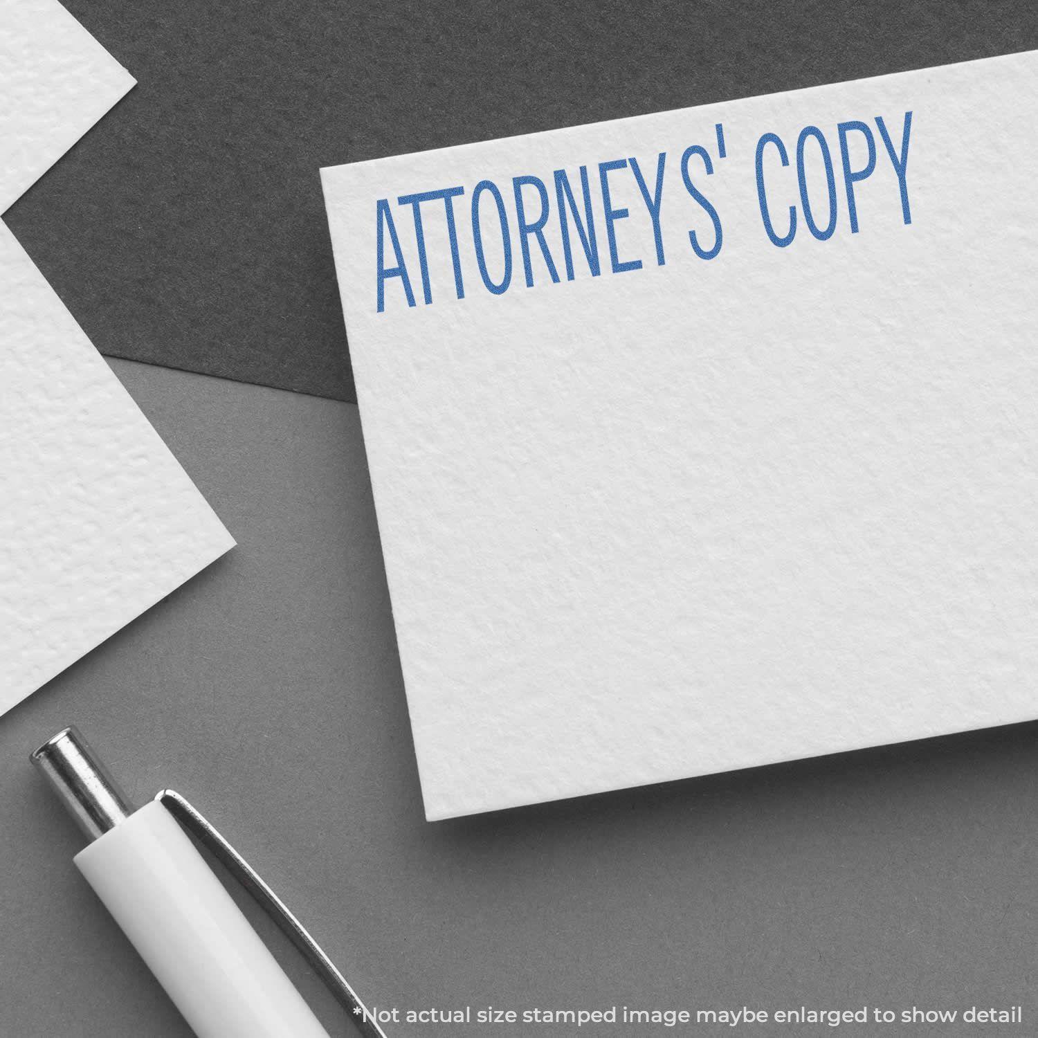 Attorney's Copy Xstamper Stamp imprint on white paper, with a pen nearby. Text reads 'ATTORNEY'S COPY' in blue.