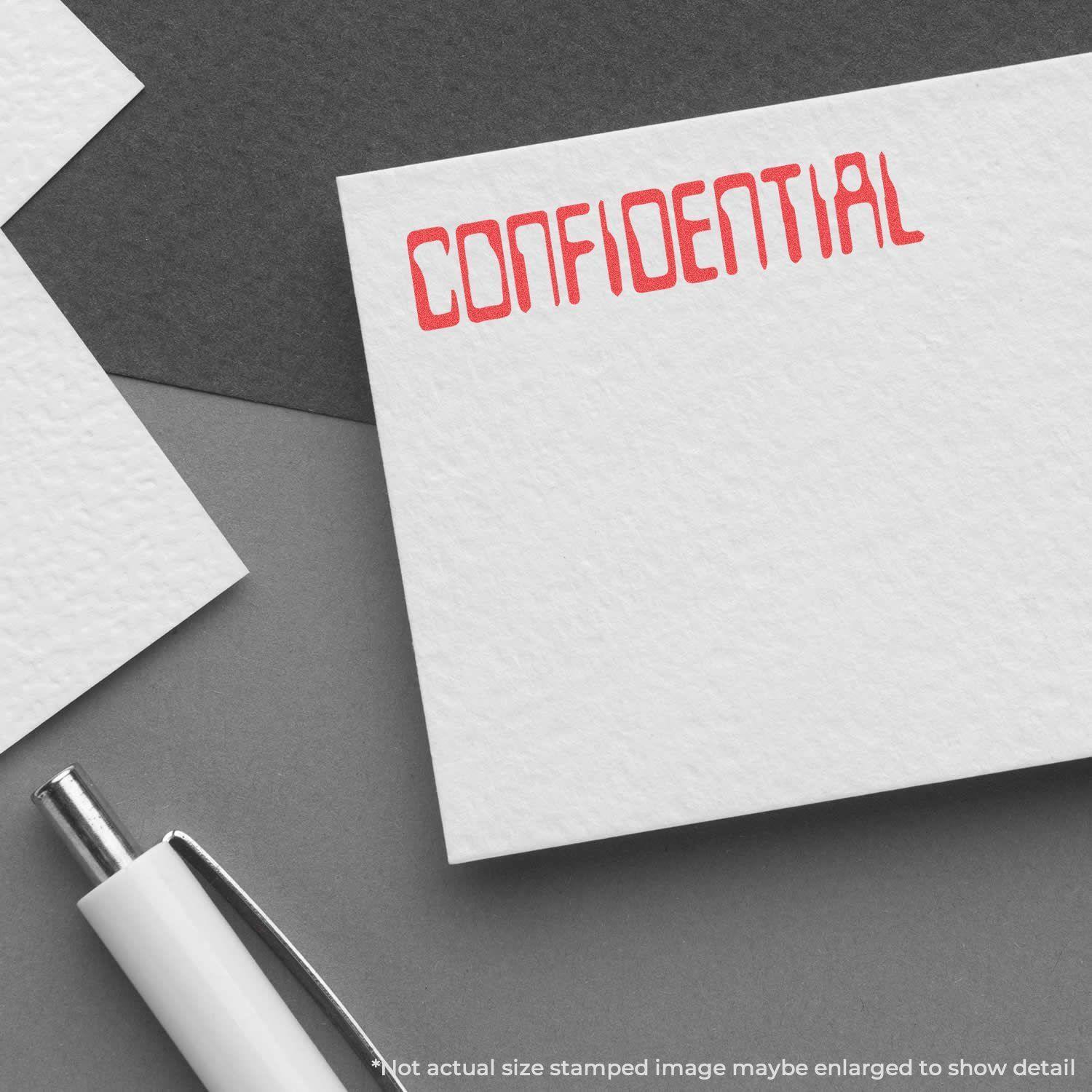 Barcode Confidential Xstamper Stamp imprinting CONFIDENTIAL in red on white paper, with a pen nearby on a gray surface.