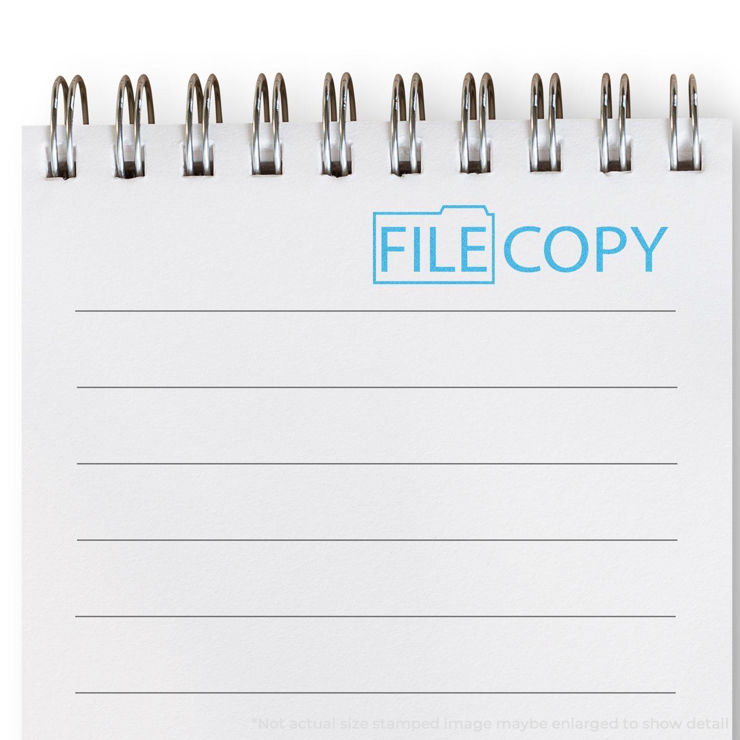 A Blue File Copy Xstamper Stamp imprint on a white spiral notebook, displaying the words FILE COPY in blue with a folder icon.