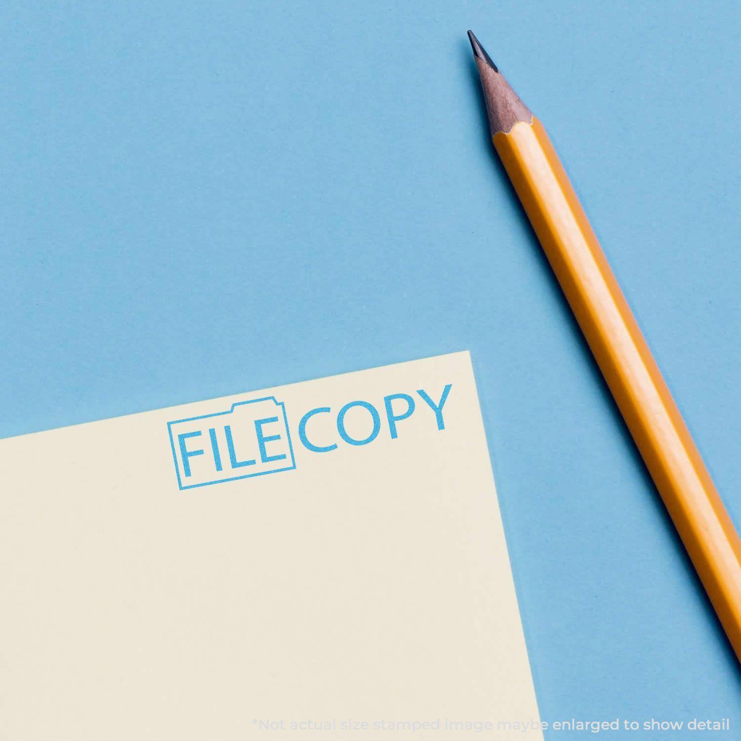 A yellow pencil next to a stamped document with FILE COPY in blue ink using the Blue File Copy Xstamper Stamp on a blue background.