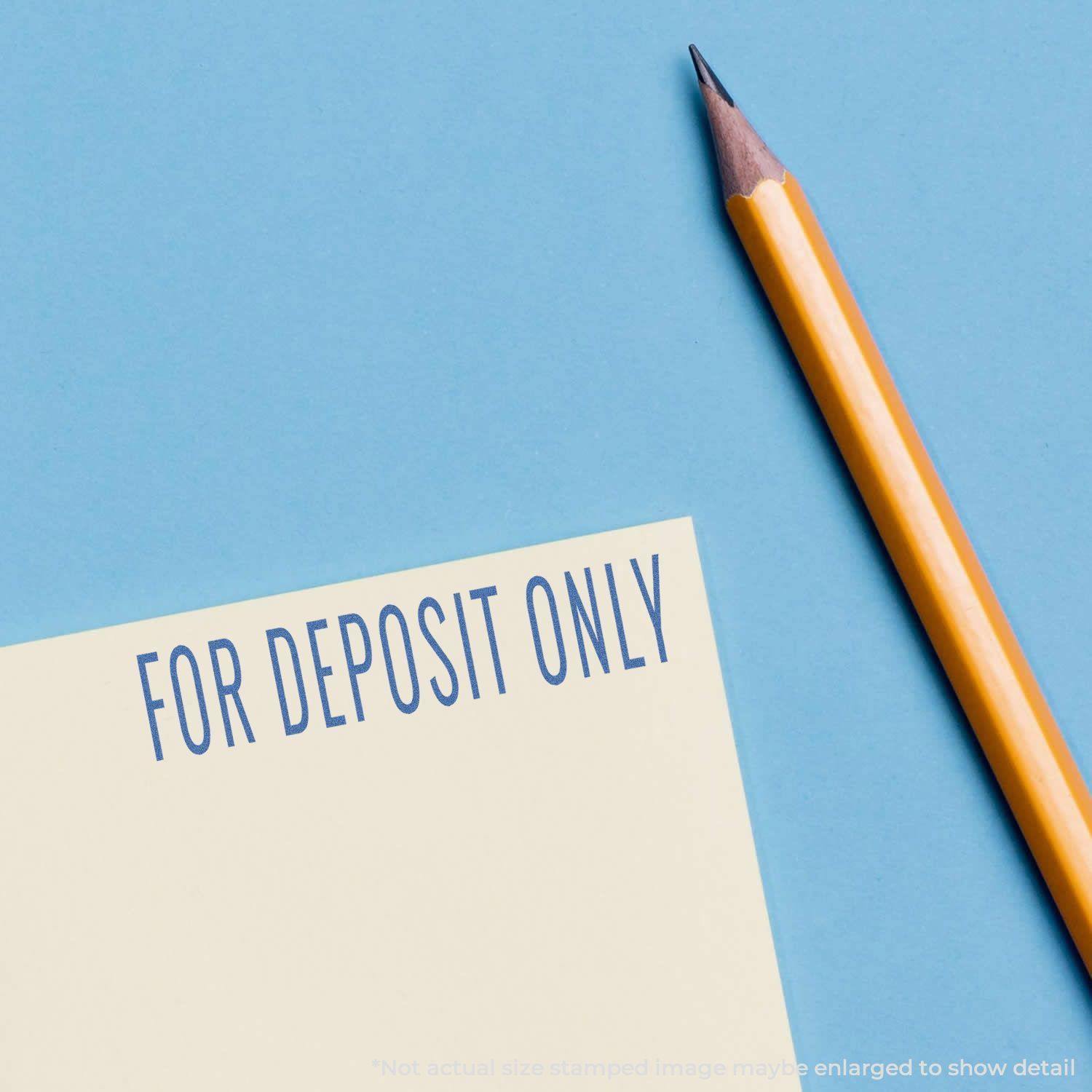 Blue For Deposit Only Xstamper Stamp imprint on paper, next to a sharpened yellow pencil on a blue background.