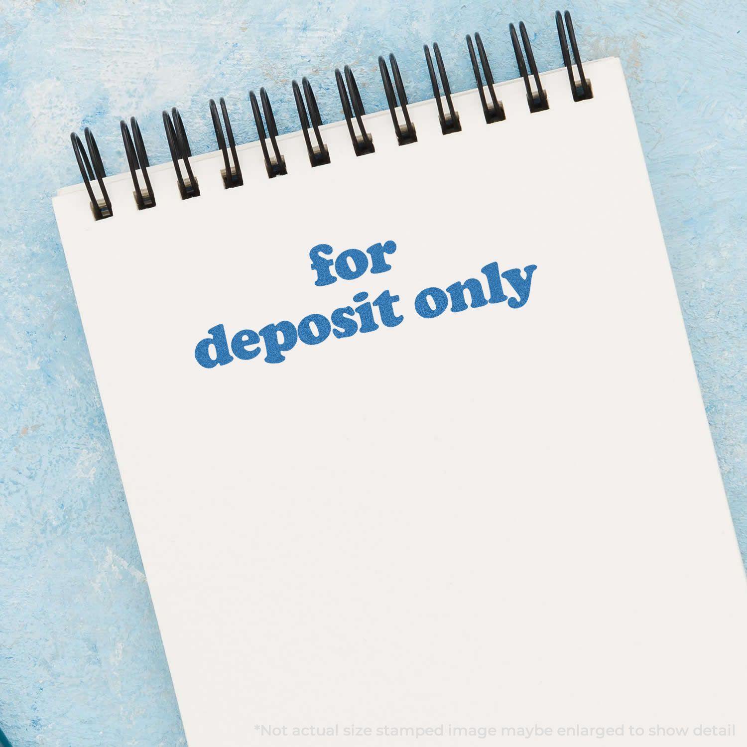 Bold Blue For Deposit Only Xstamper Stamp imprint on a white notepad with a blue background.