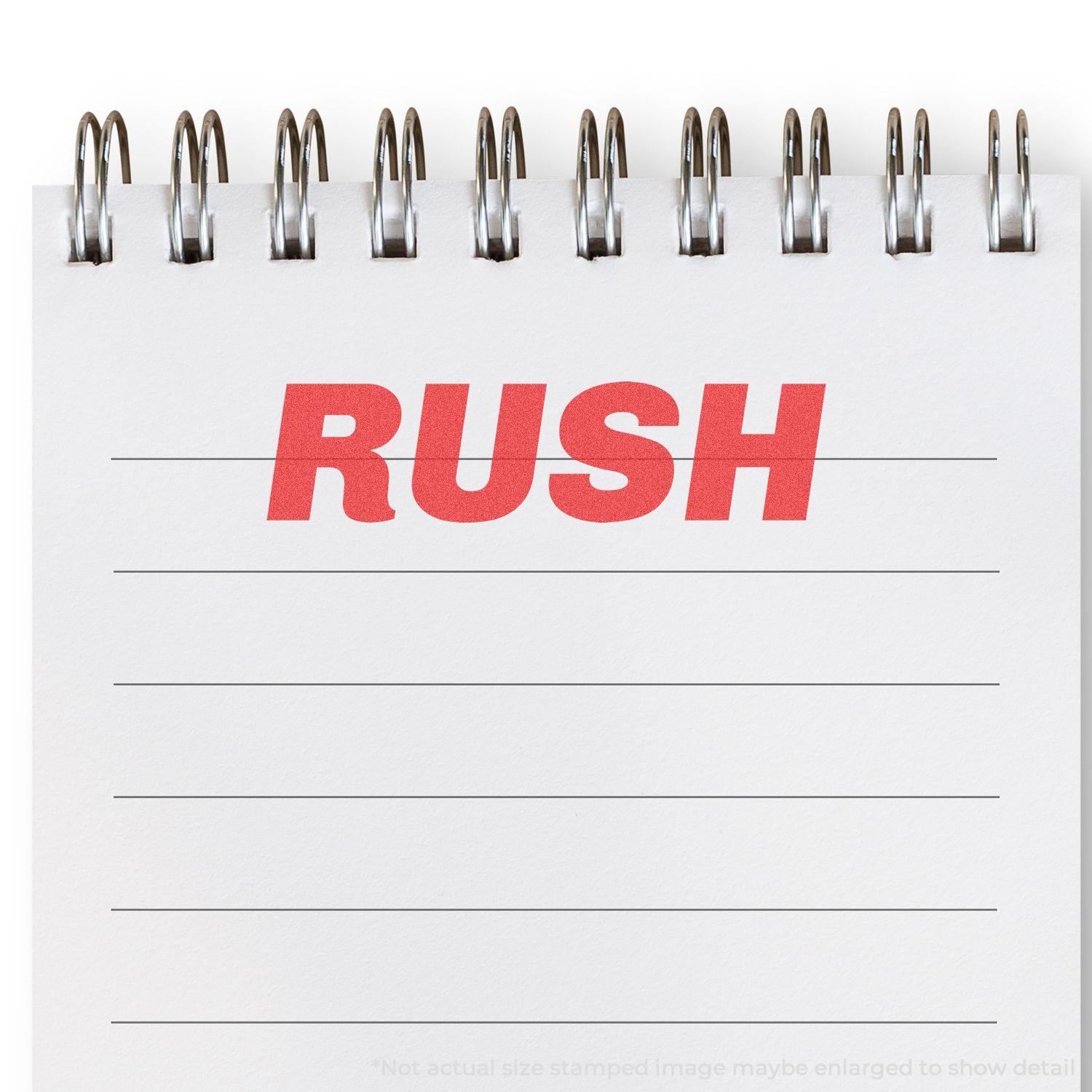 Bold Red Rush Xstamper Stamp imprint on a white spiral notebook with lined paper, displaying the word RUSH in bold red letters.