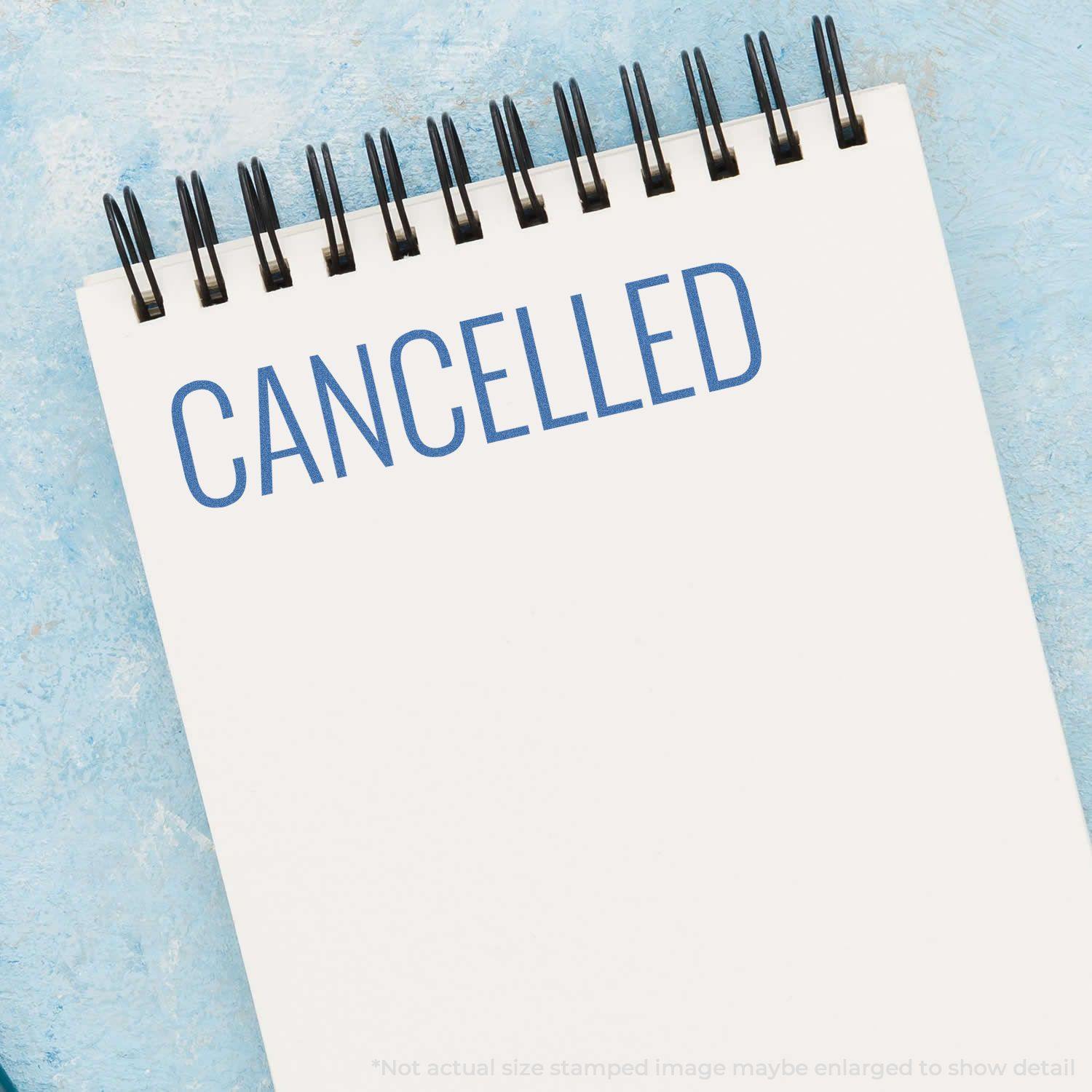 Cancelled Xstamper Stamp imprint on a white notepad with a blue background. The word 'CANCELLED' is stamped in blue ink.