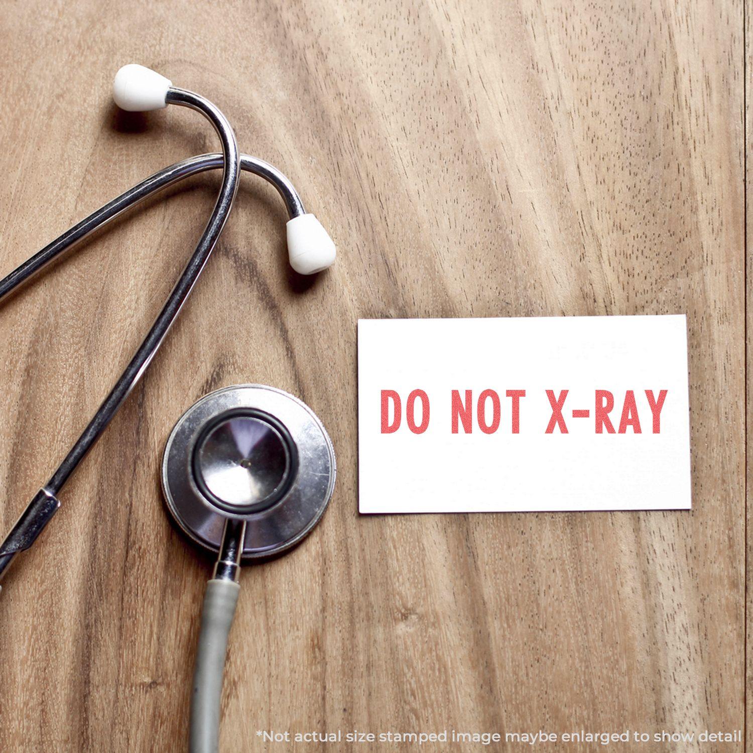 A stethoscope on a wooden surface next to a card stamped with DO NOT X-RAY using the Do Not X-Ray Xstamper Stamp.