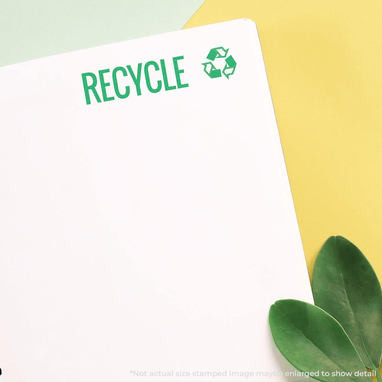 Green Recycle Xstamper Stamp imprint on white paper with green RECYCLE text and recycling symbol, placed on a yellow and green background.