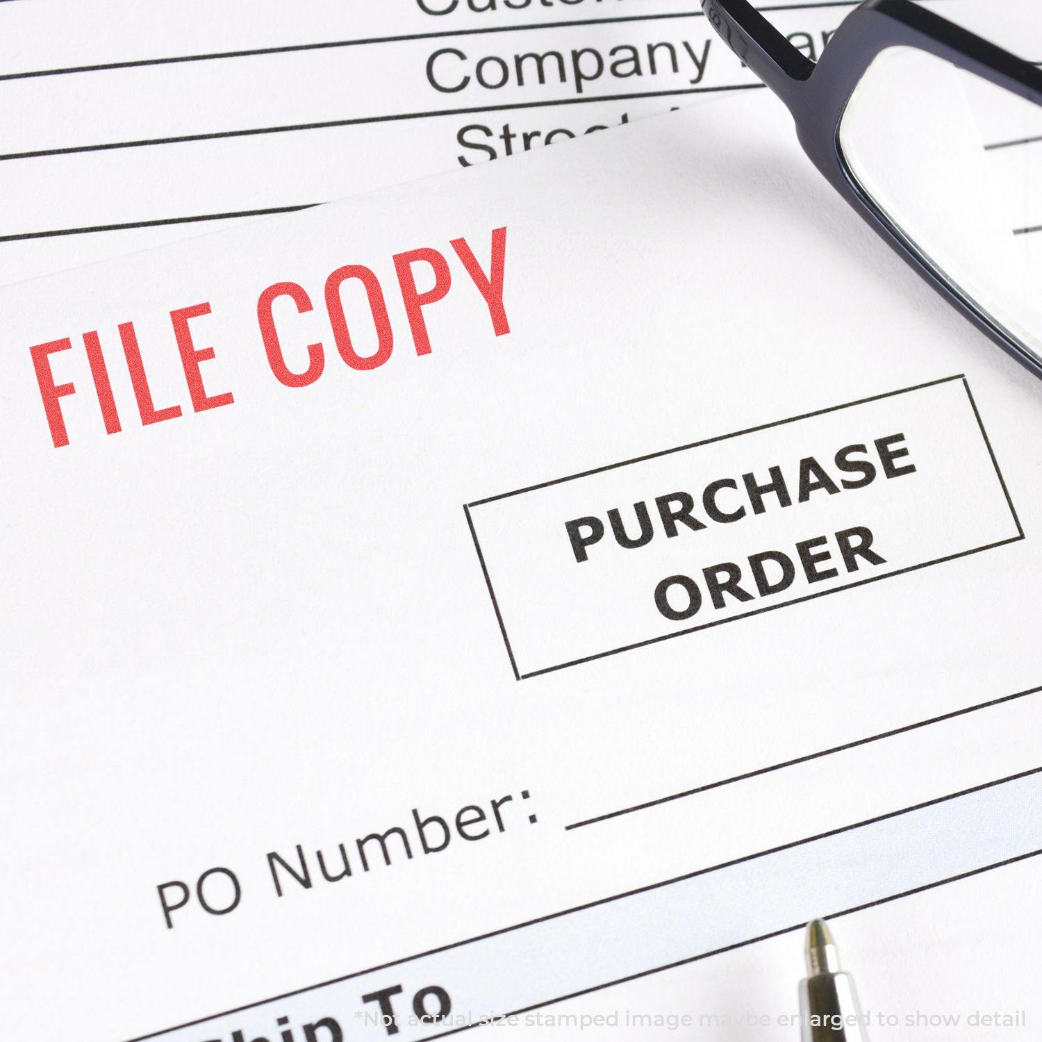 A document stamped with FILE COPY in red using the Red File Copy Xstamper Stamp, with a purchase order form, pen, and glasses nearby.