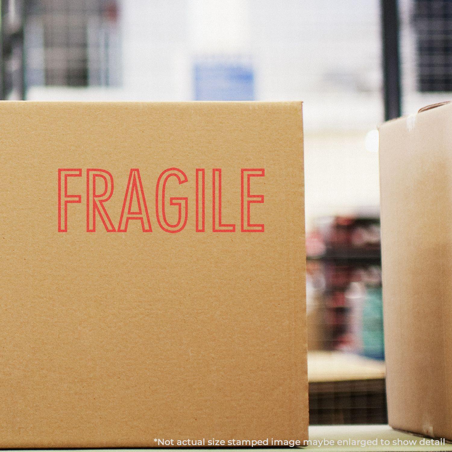 A cardboard box stamped with FRAGILE in red ink using the Red Fragile Xstamper Stamp, placed in a warehouse setting.