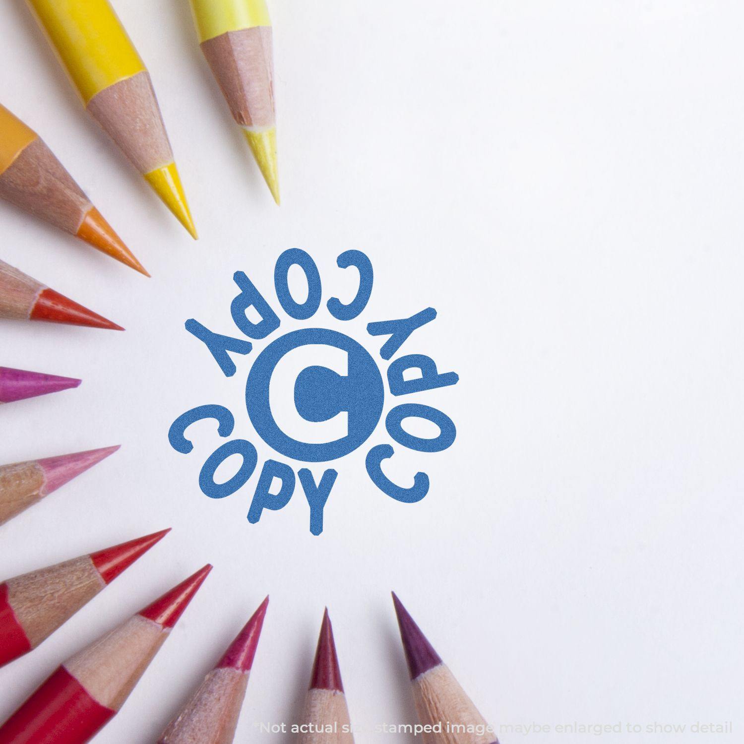 Round Blue Copy Xstamper Stamp impression on white paper surrounded by colored pencils.