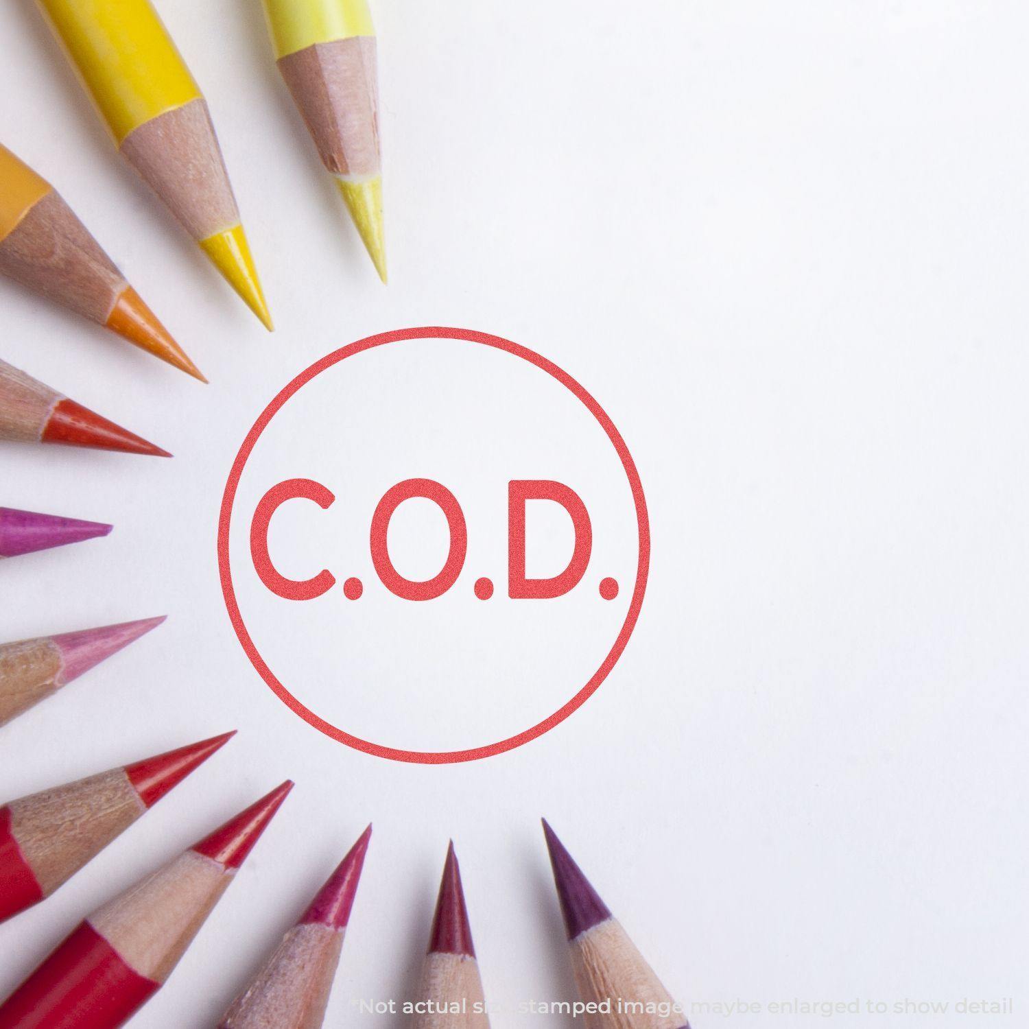 Round C.O.D. Xstamper Stamp imprint on white paper, surrounded by colored pencils arranged in a circular pattern.