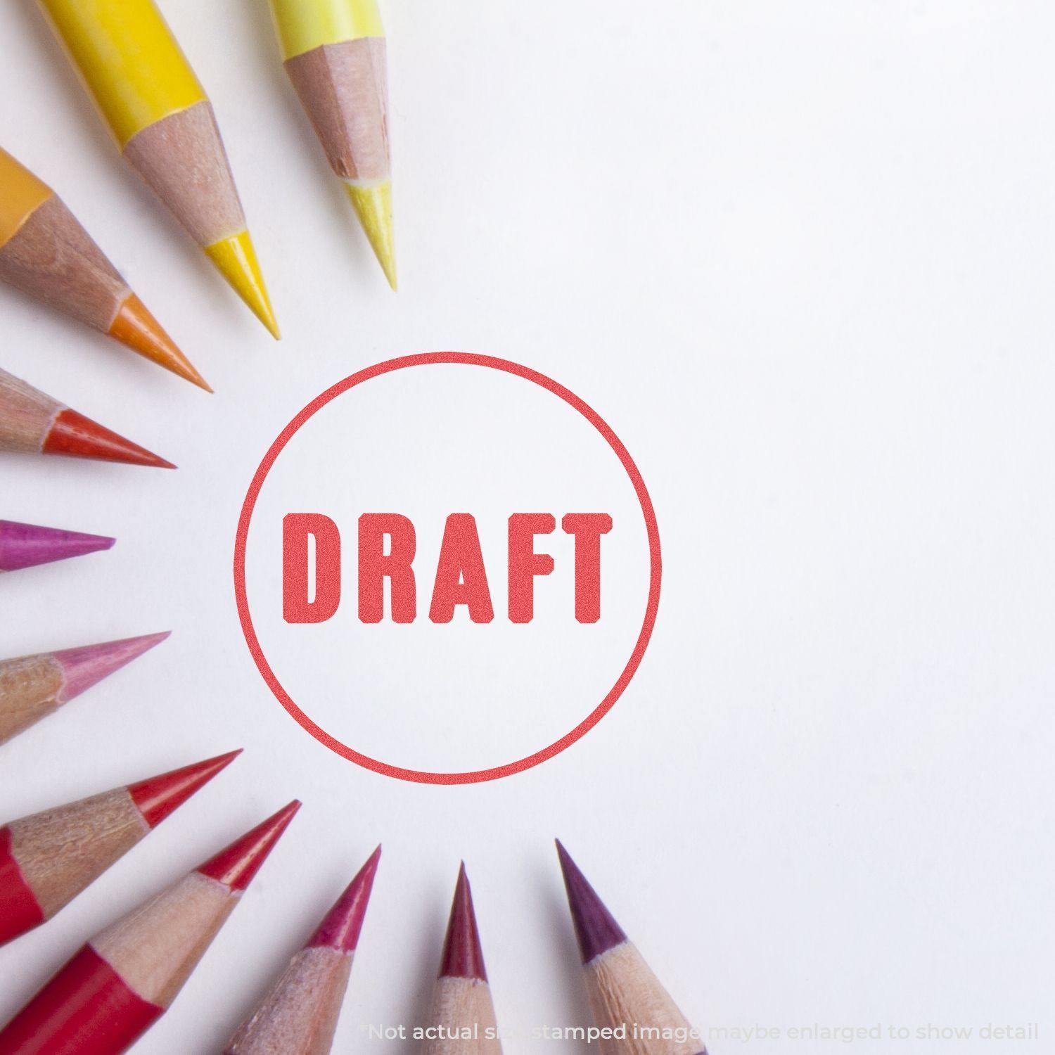 Round Draft Xstamper Stamp imprint on white paper surrounded by colored pencils arranged in a semicircle.